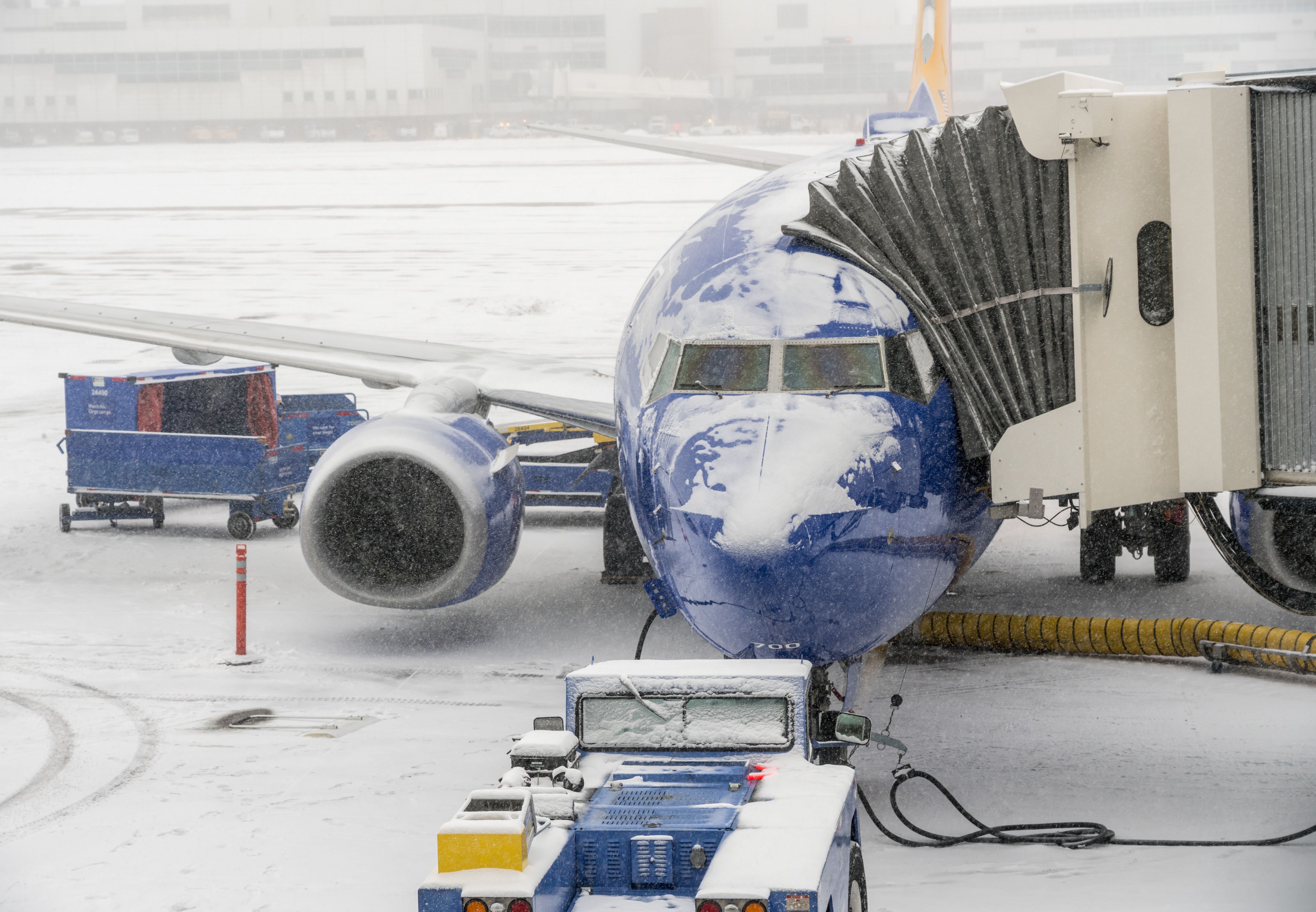 A snow-covered Southwest Airlines Boeing 737 parked at a gate at Denver International Airport.