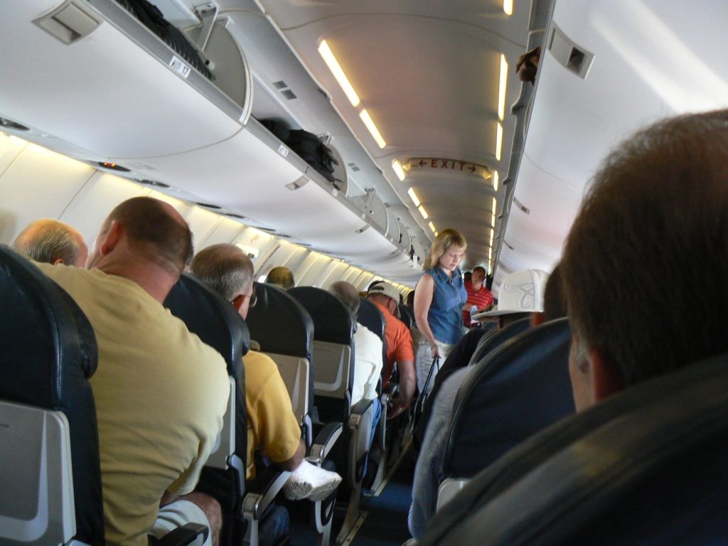 A passenger standing in the aisle during flight.