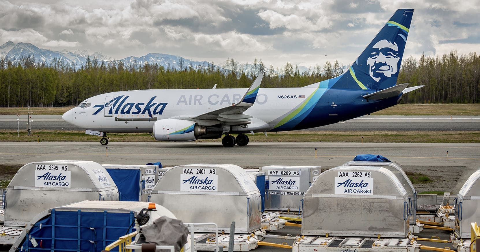 An Alaska Airlines Boeing 737-700 Freighter taxiing behind Alaska Air Cargo containers.