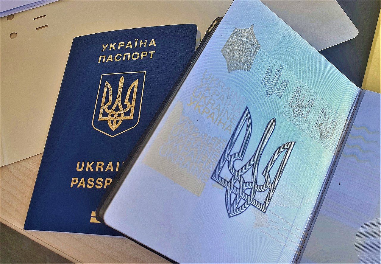 Two Ukrainian passports, one closed, one open, showing the coat of arms of Ukraine.
