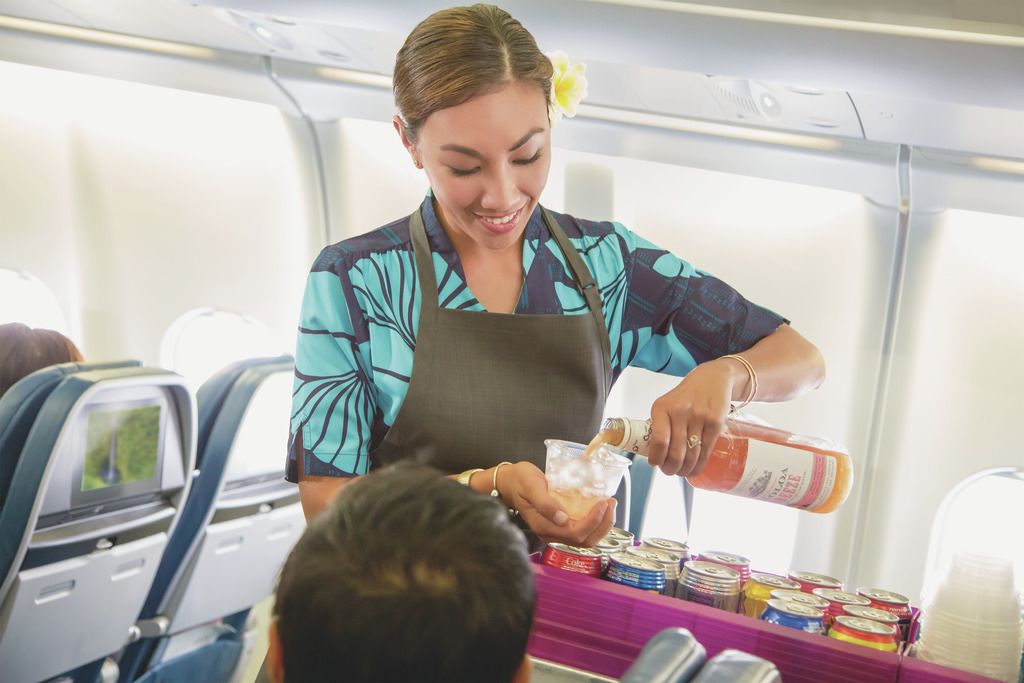 A Hawaiian Airlines Flight Attendant serving beverages.