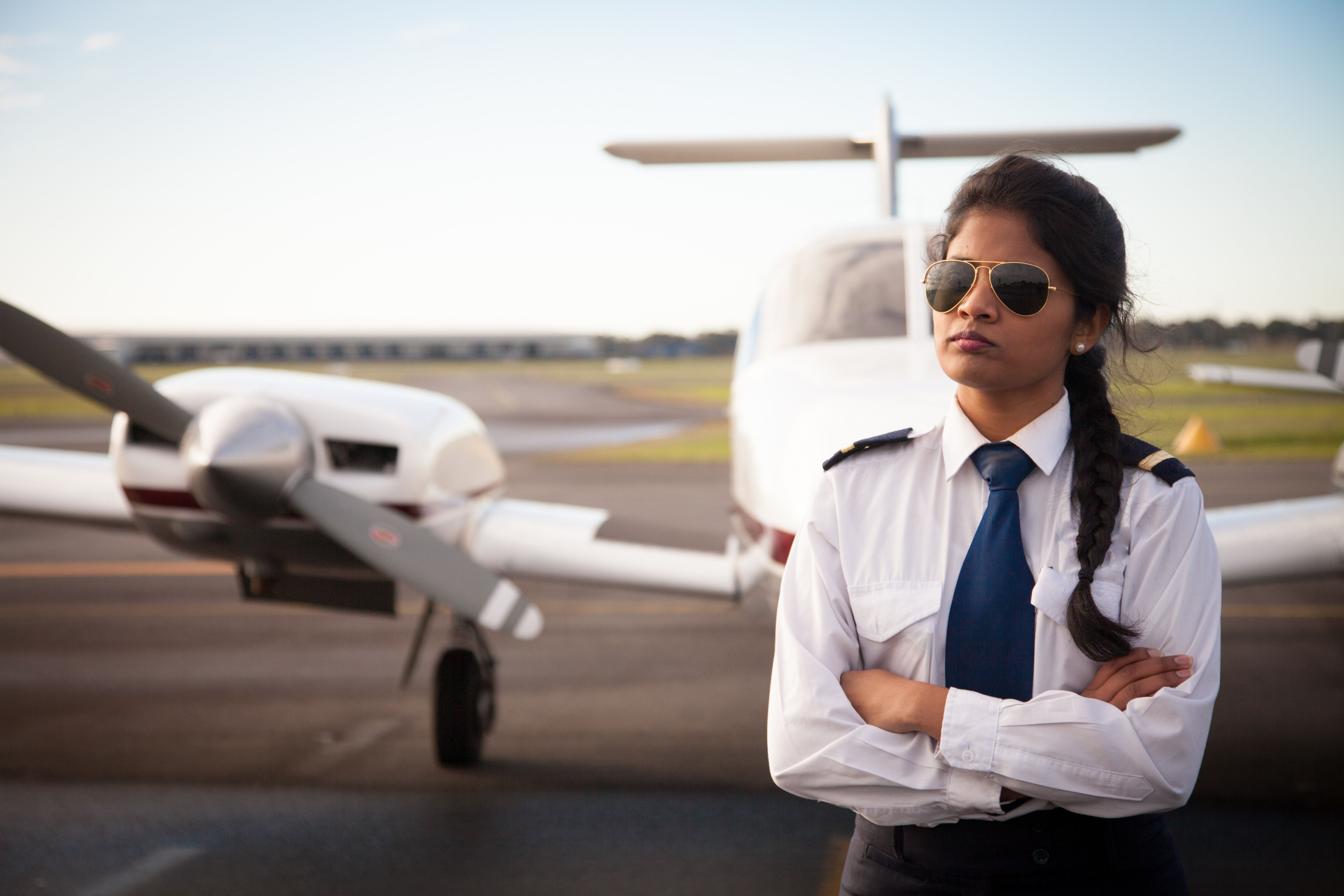 A female pilot in front of a general aviation aircraft.