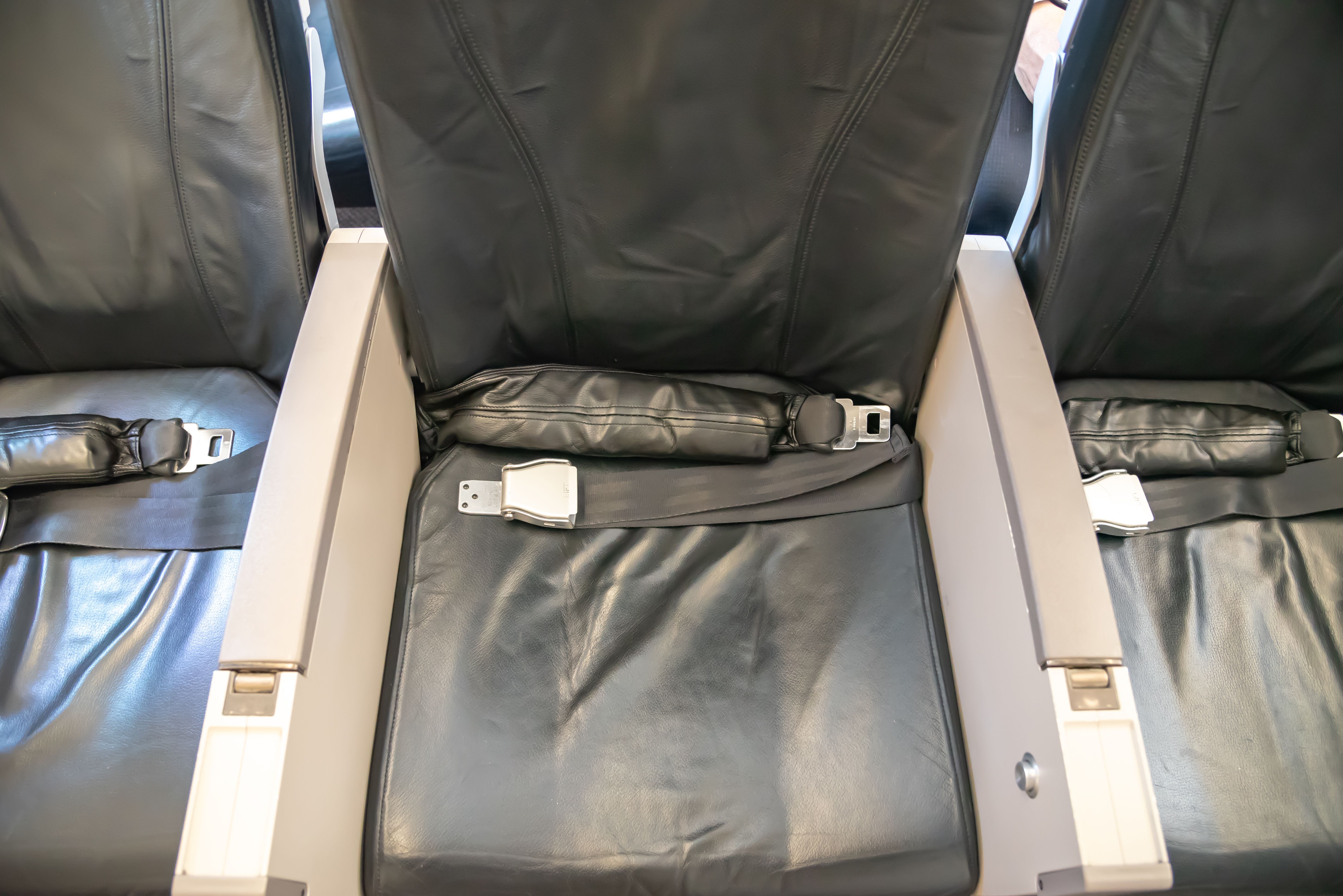 Economy class seat with an airbag installed within the seatbelt