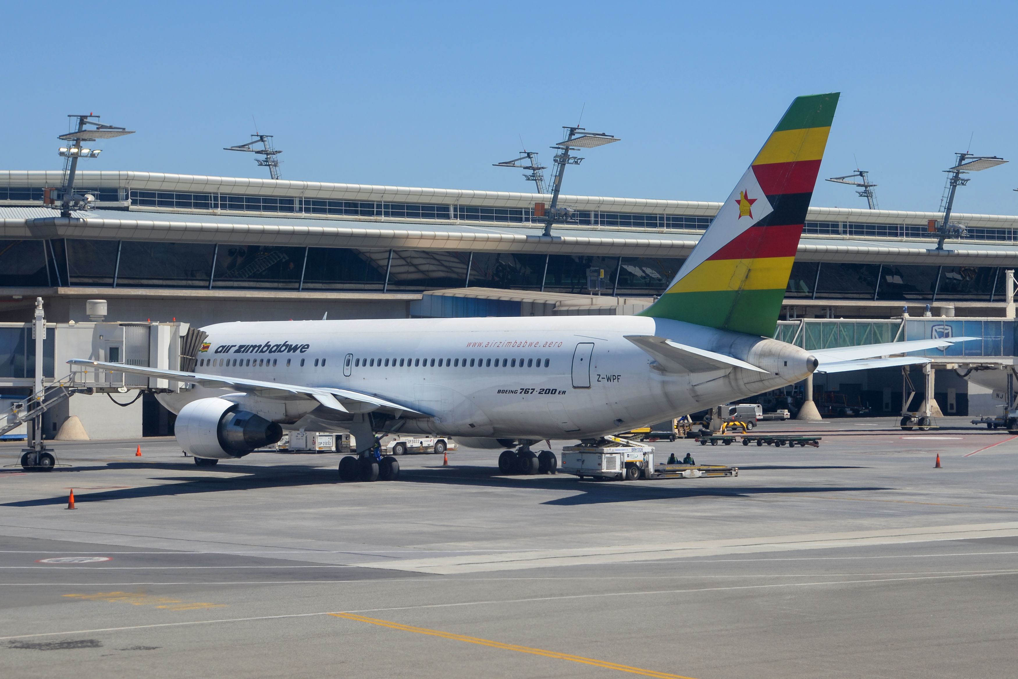 An Air Zimbabwe Boeing 767 parked on an airport apron at a gate.