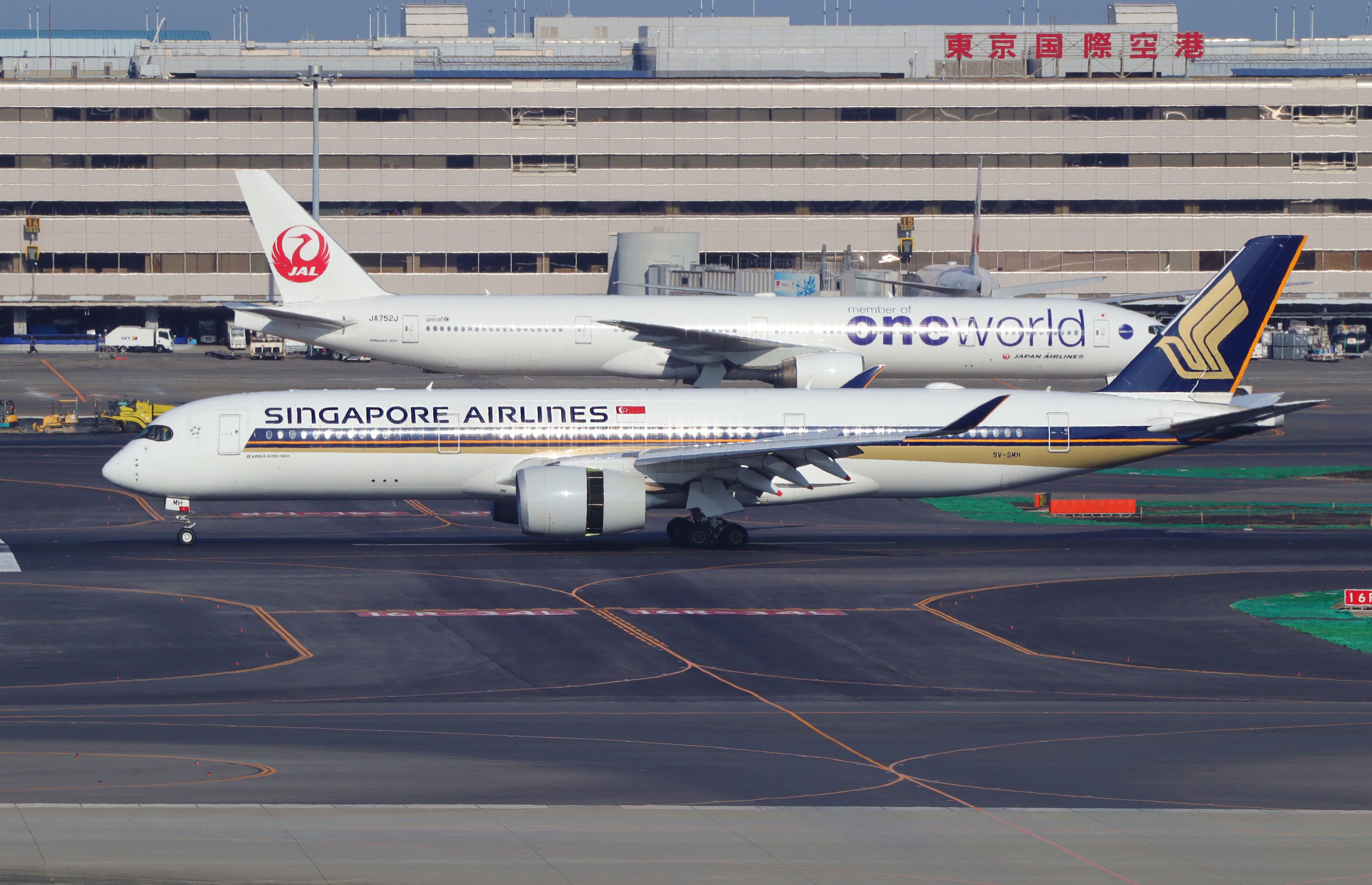 A Japan Airlines Boeing 777 and Singapore Airlines Airbus A350 on an airport apron.