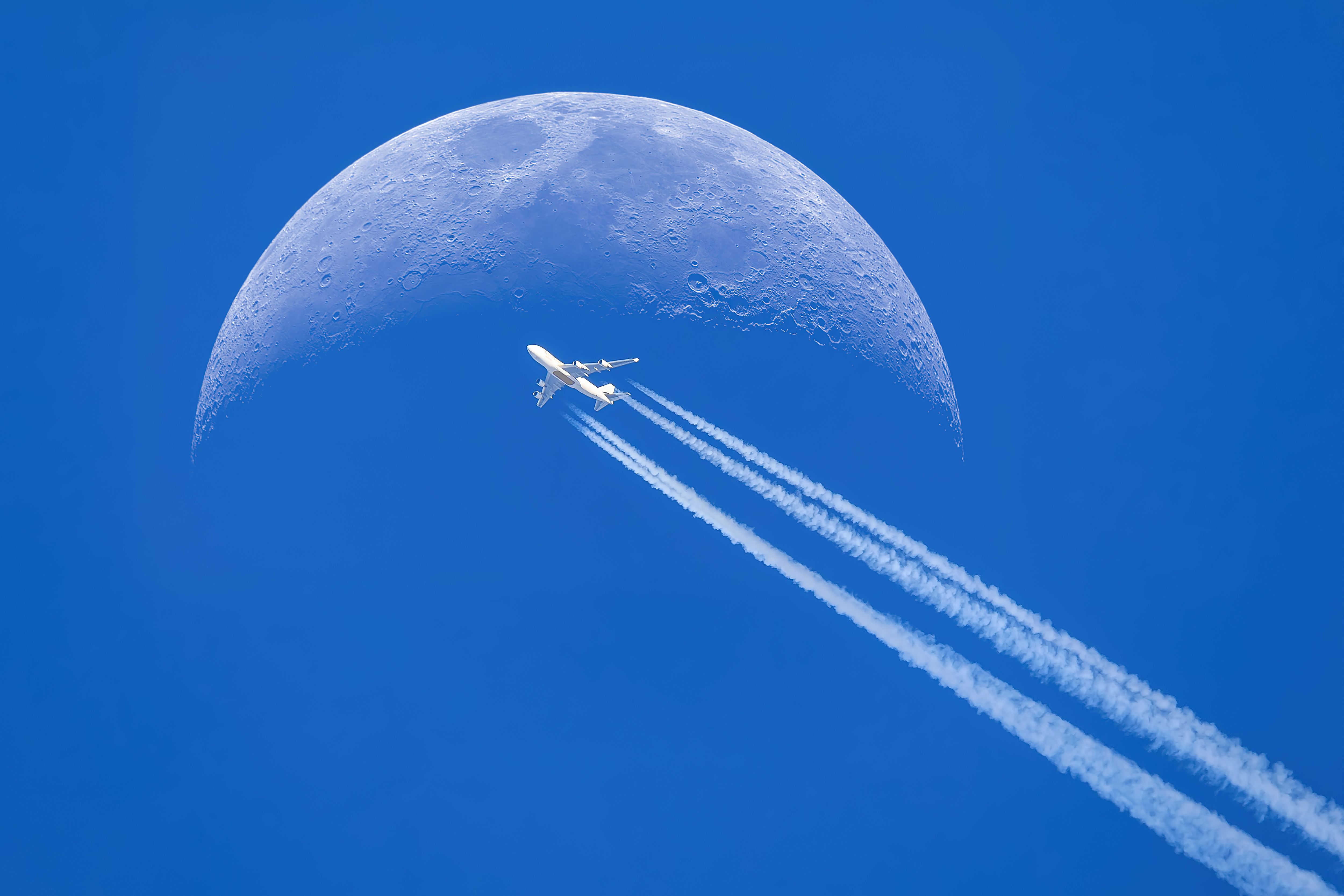 An Emirates A380 silhouettes the moon. 