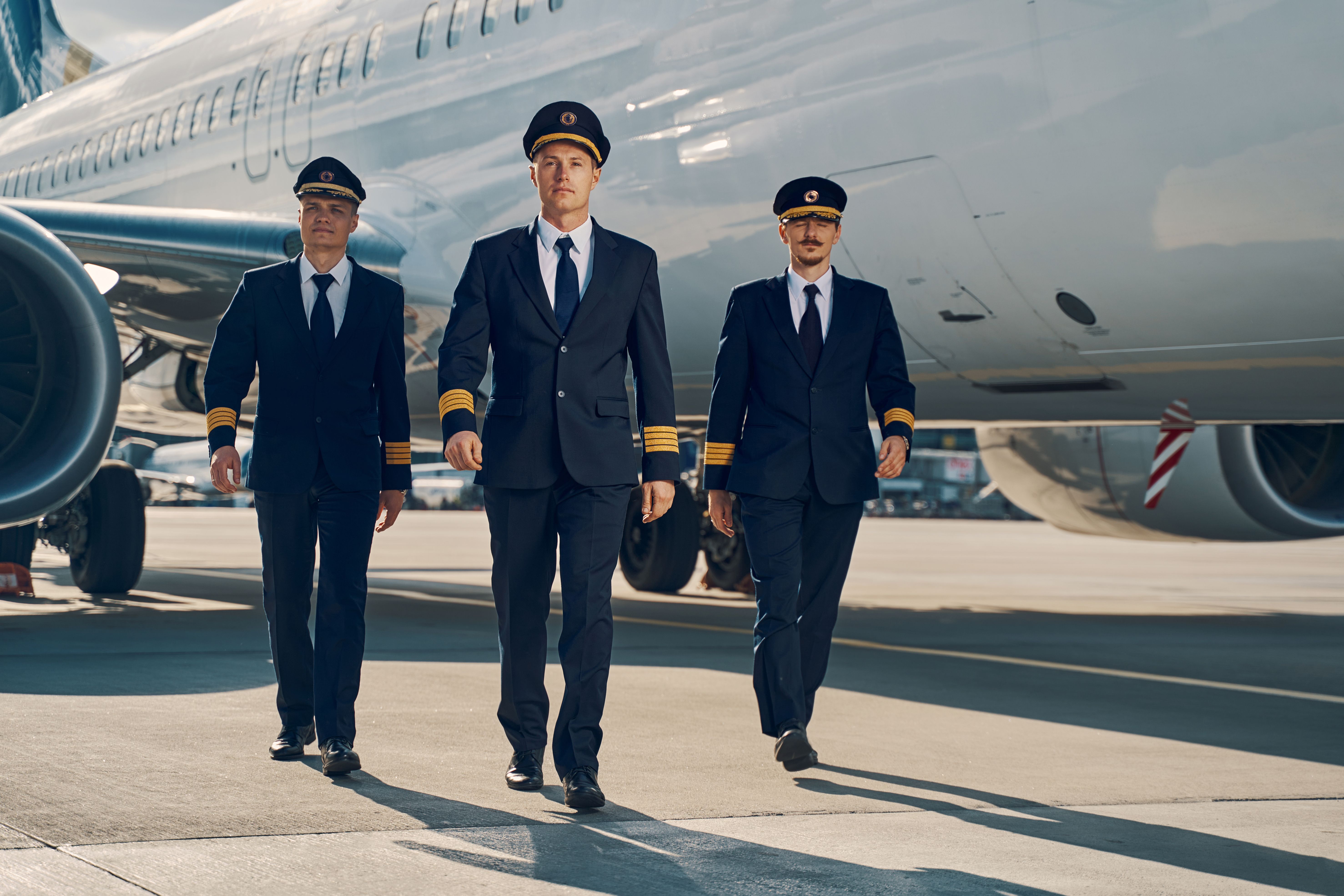 Three pilots standing near a parked aircraft.