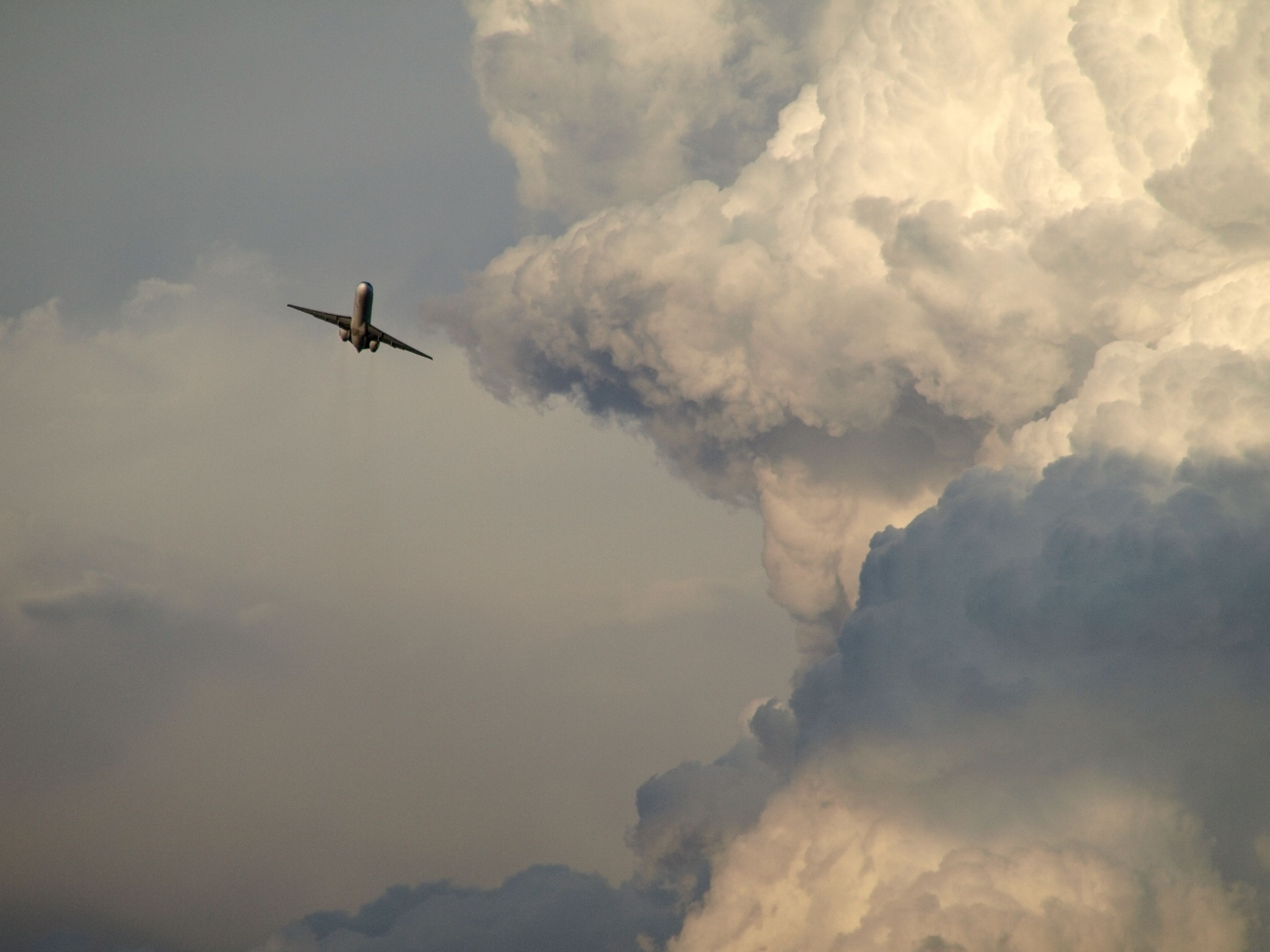 An aircraft banking around storm clouds.