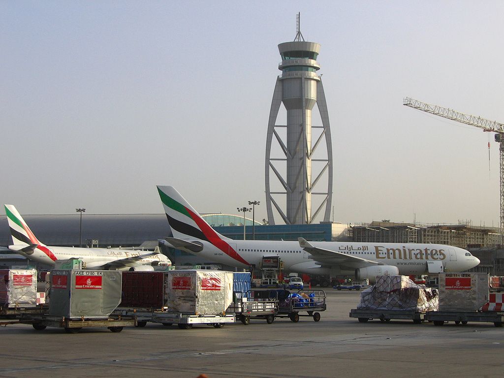 Multiple Emirates aircraft lined up near cargo containers.