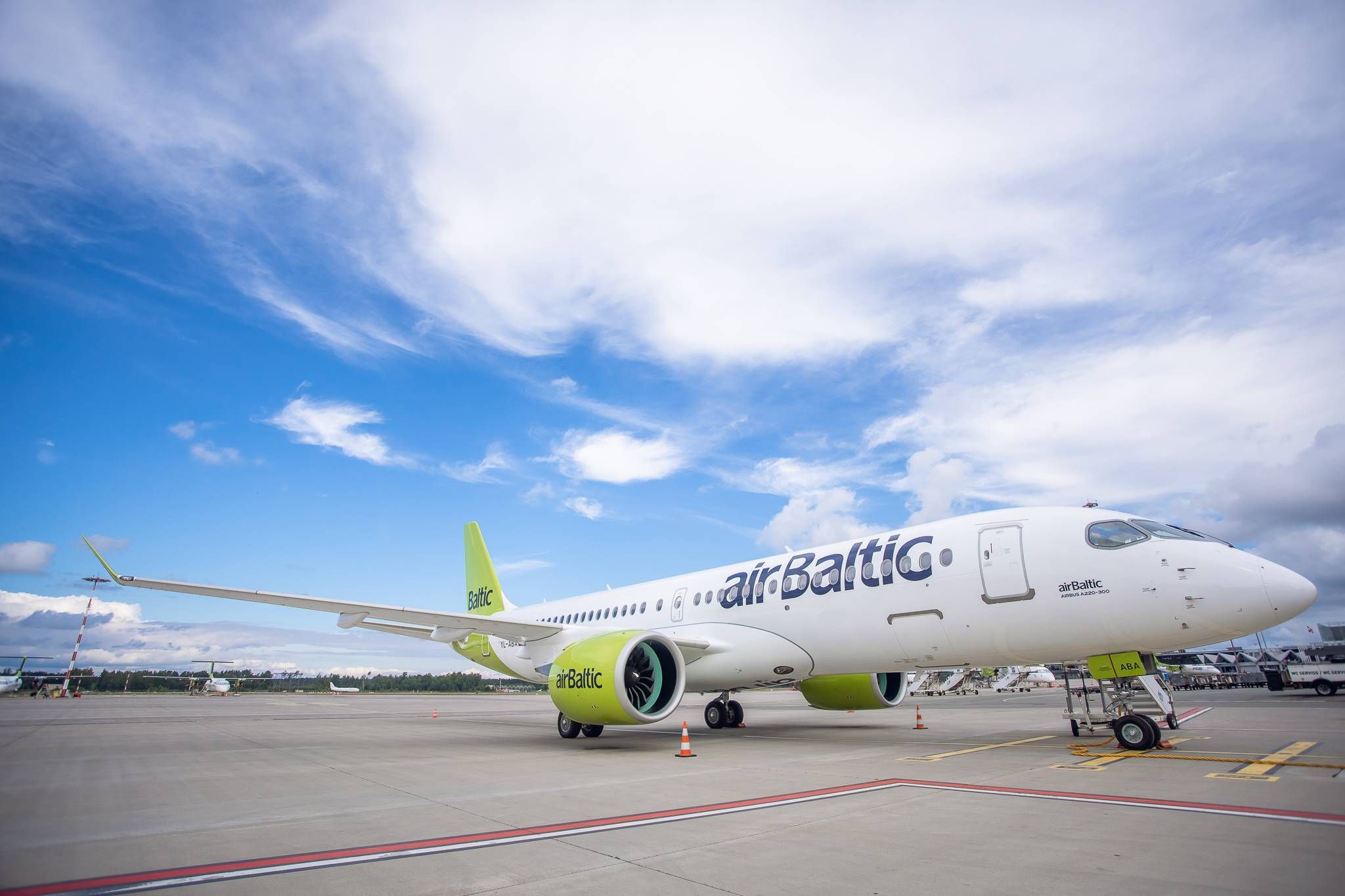 An airBaltic Airbus A220-300 parked at an airport.