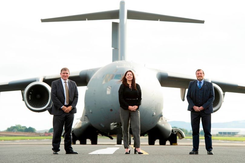 Company leaders standing in front of a C-17 on the runway.