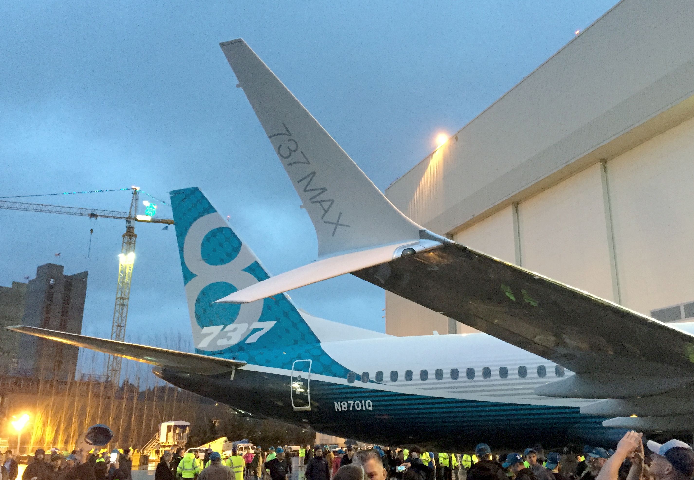 Employees stand near a Boeing 737 MAX parked right outside a hanger. 
