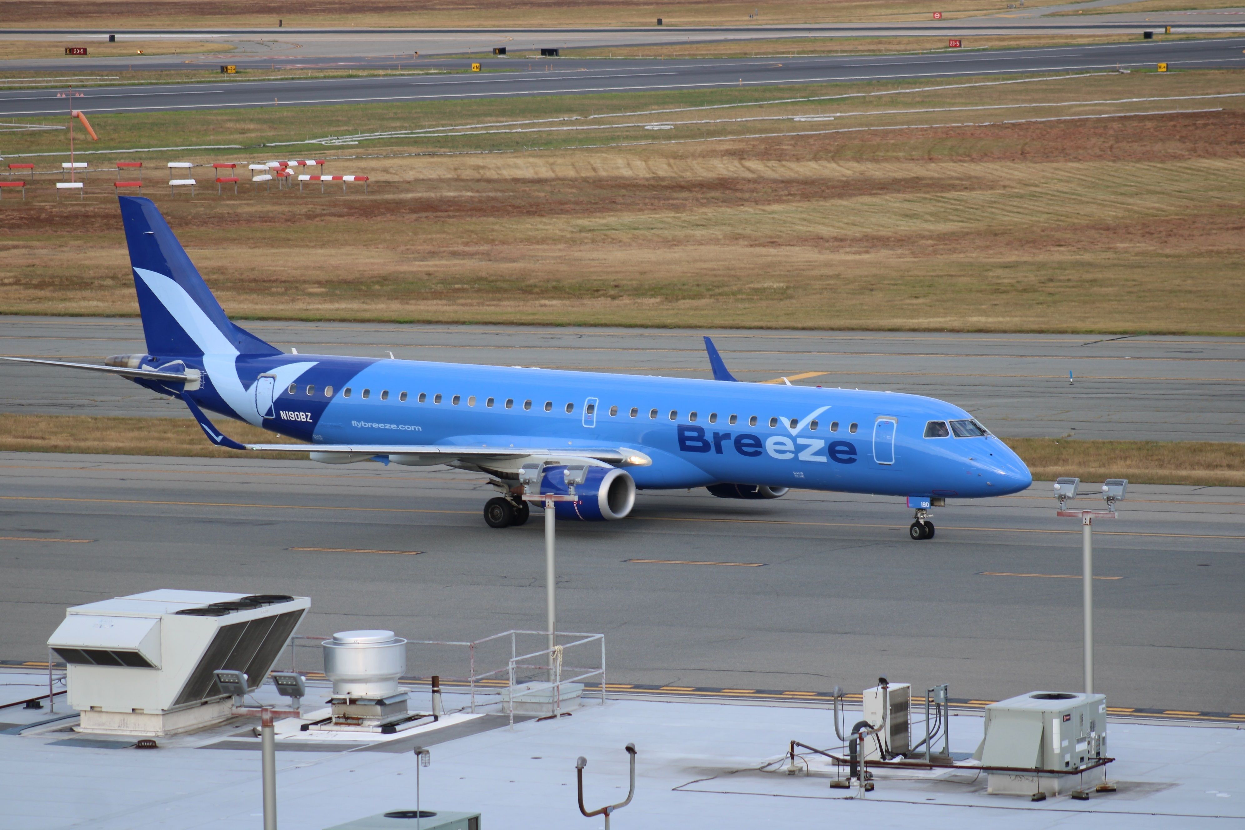 A Breeze Airways Embraer aircraft taxiing to the gate.