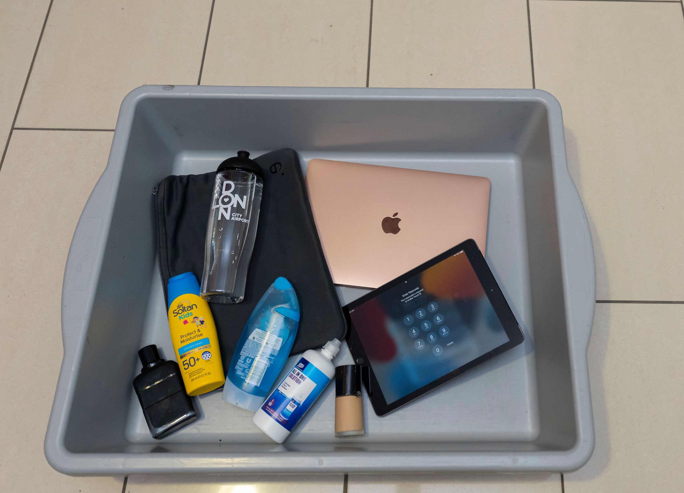 Large liquids and electronic devices in an airport security tray.