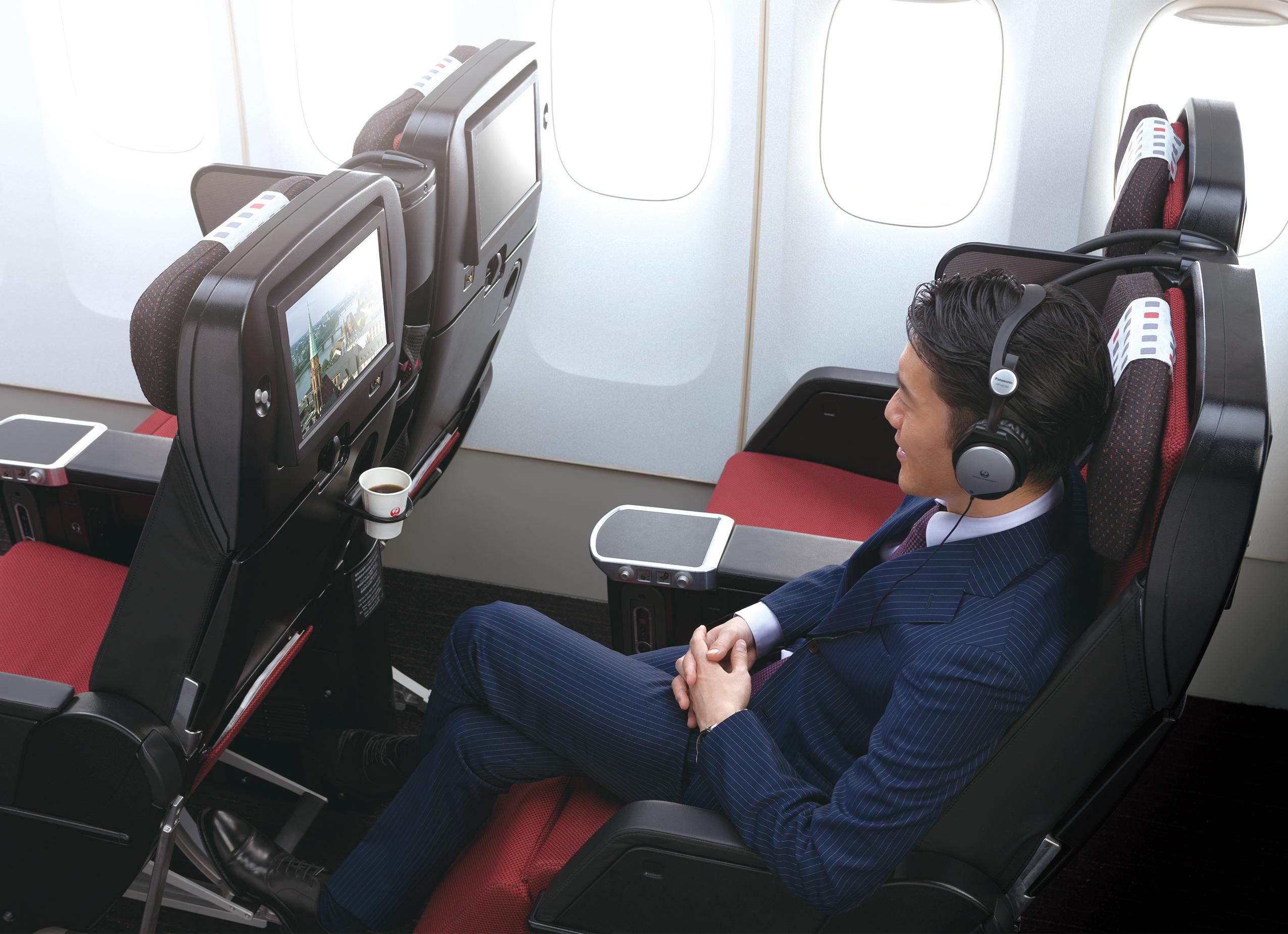 A passenger watching a movie in his seat in the JAL premium economy cabin.