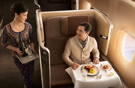 A Singapore Airlines flight attendant bringing champagne to a business class passenger.