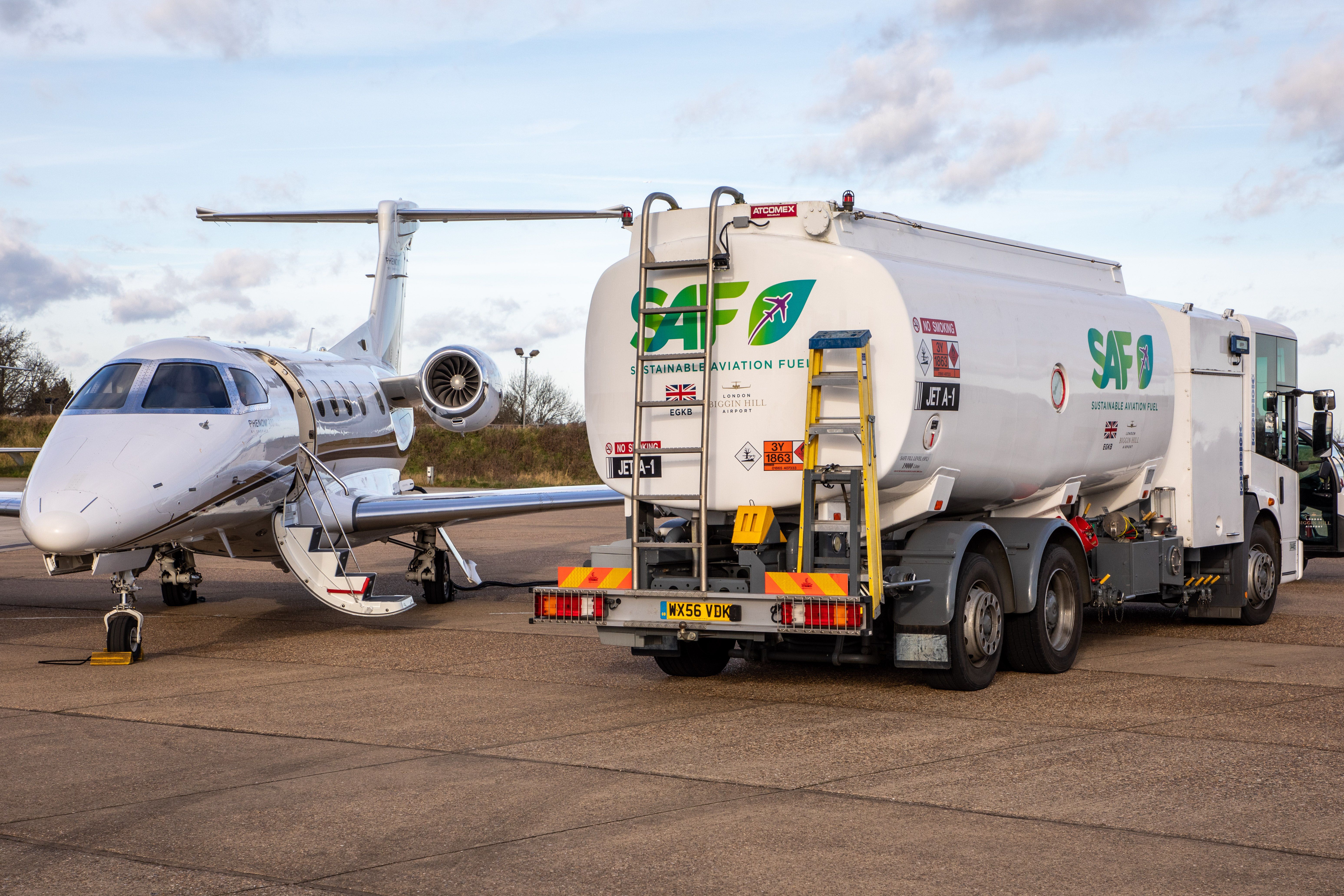 An Embraer Phenom aircraft next to a truck filled with SAF.