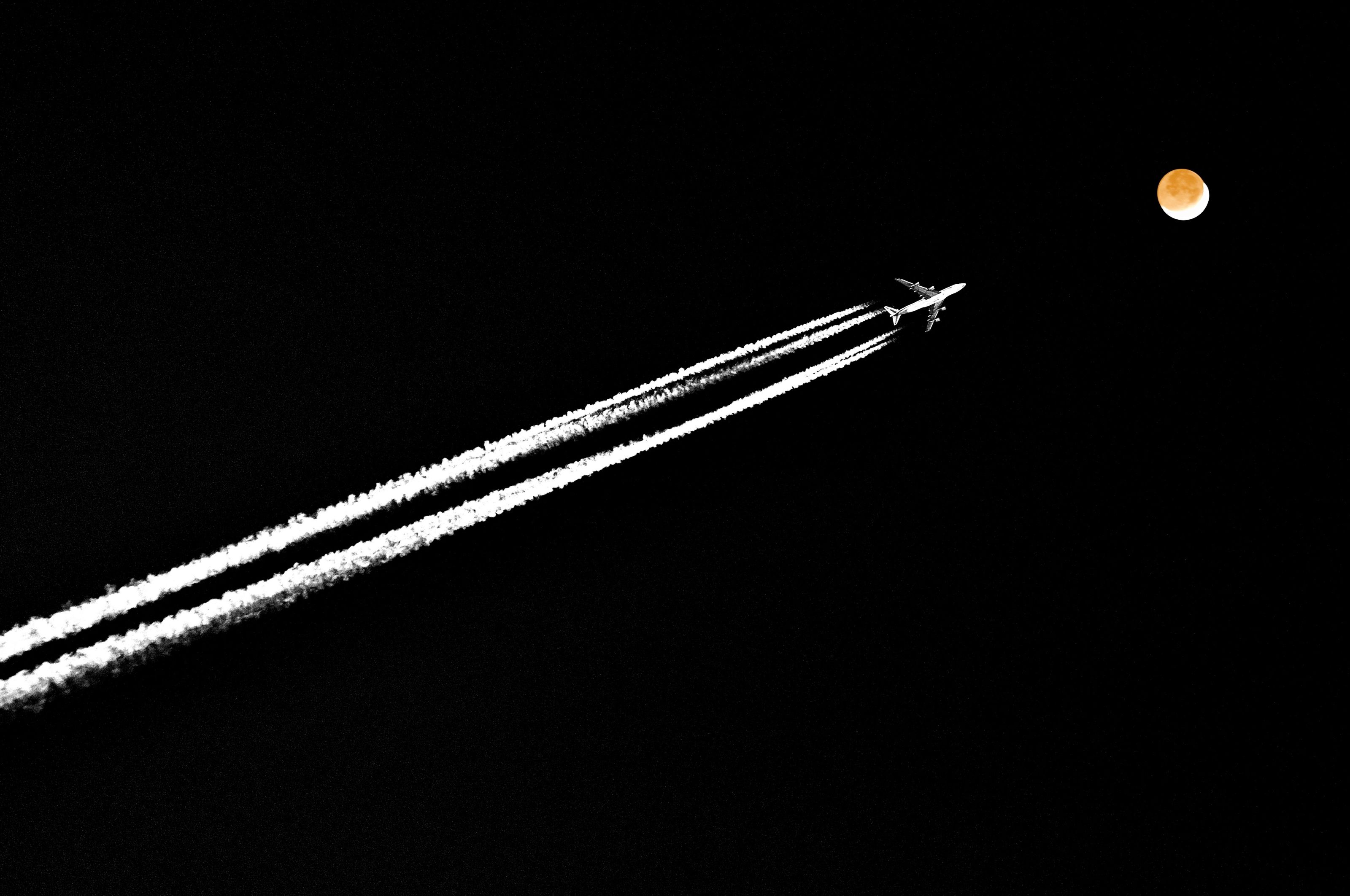A quad-engine plane silhouetted by the moon.