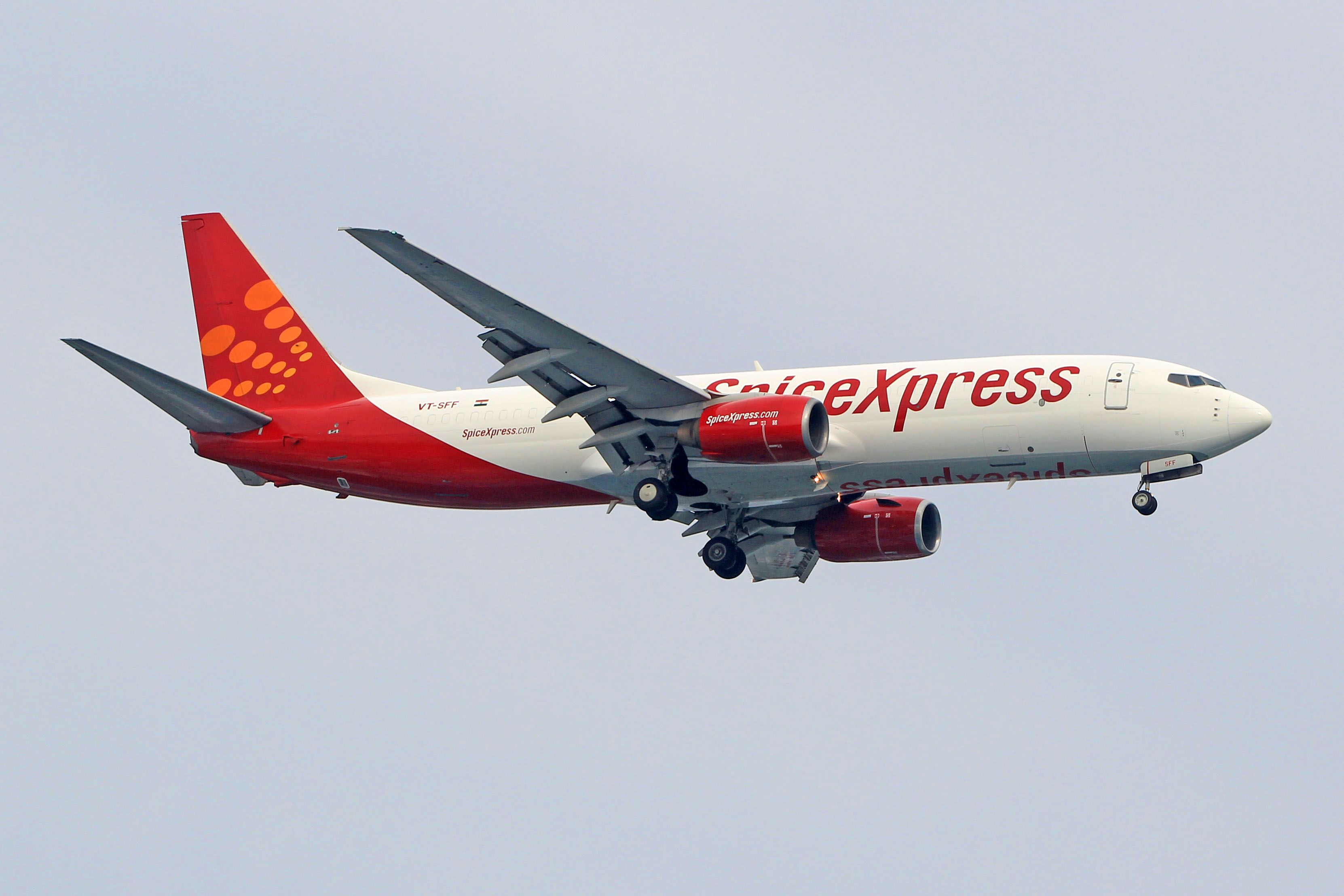 A SpiceXpress Boeing 737 freighter flying low with landing gear deployed. 