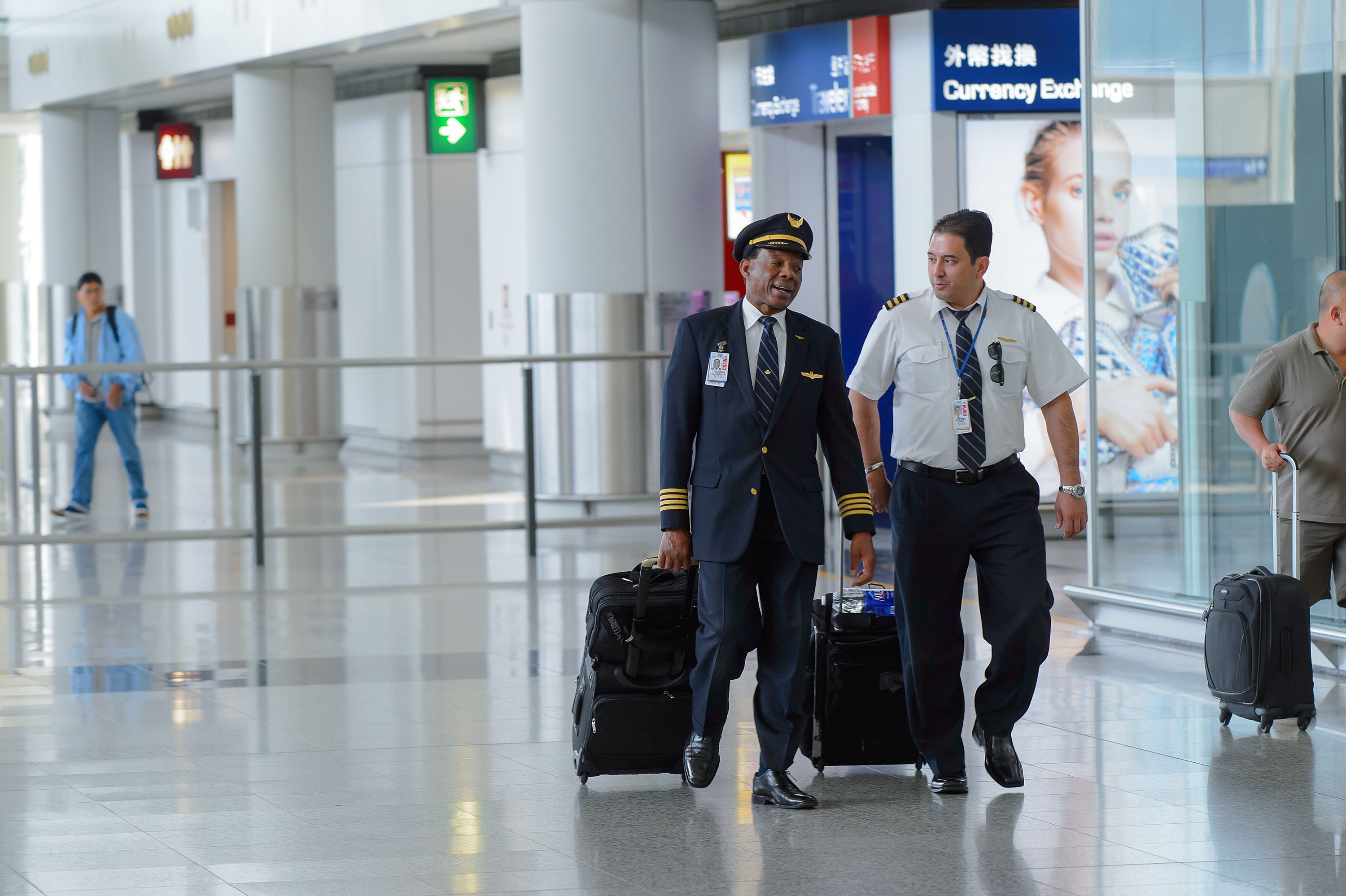 Two pilots strolling through Hong Kong Int'l Airport.