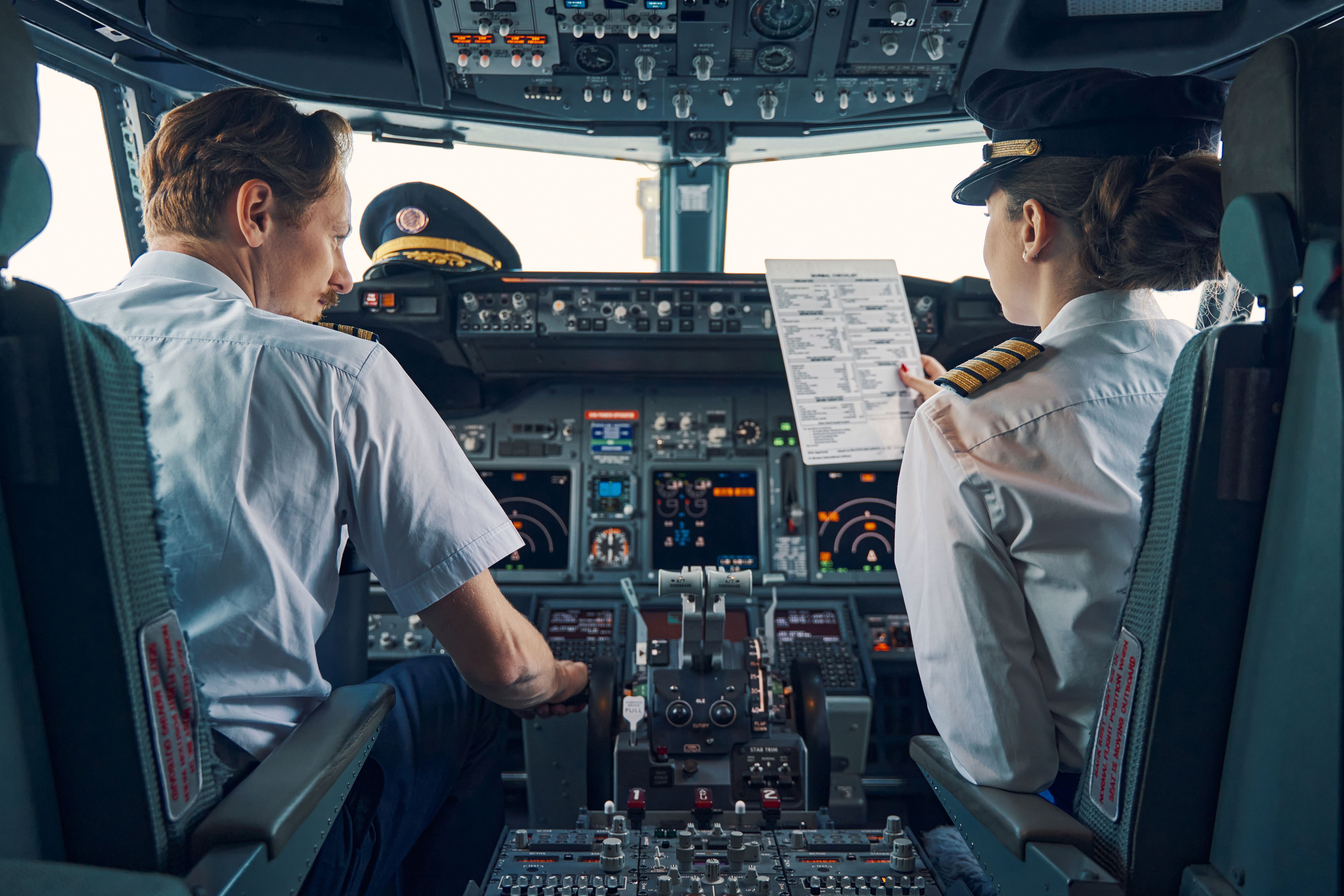 Two pilots working in the cockpit of an aircraft. 