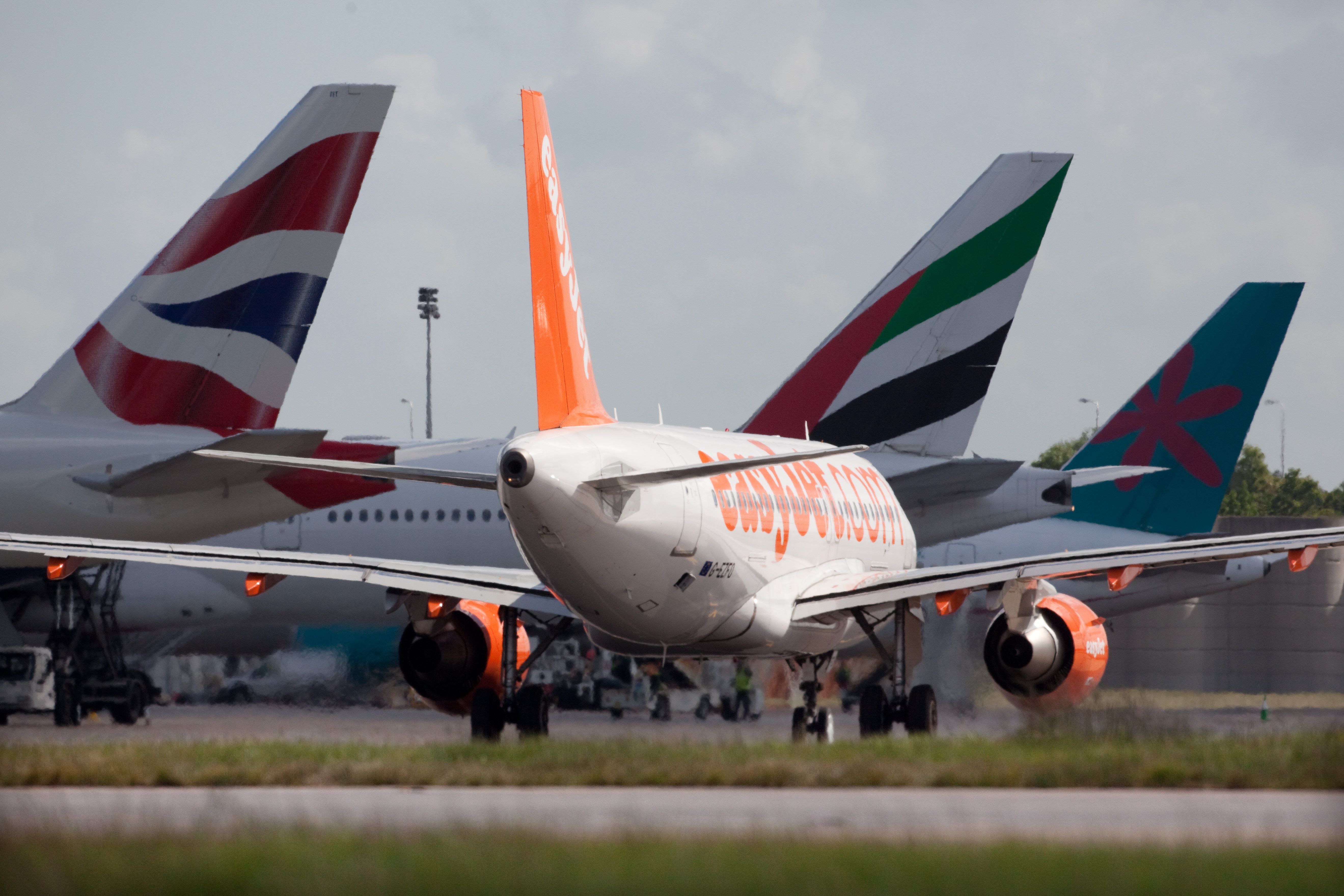gatwick-tailfins - EasyJet Airbus taxiing by British Airways, Emirates and another widebody at London Gatwick