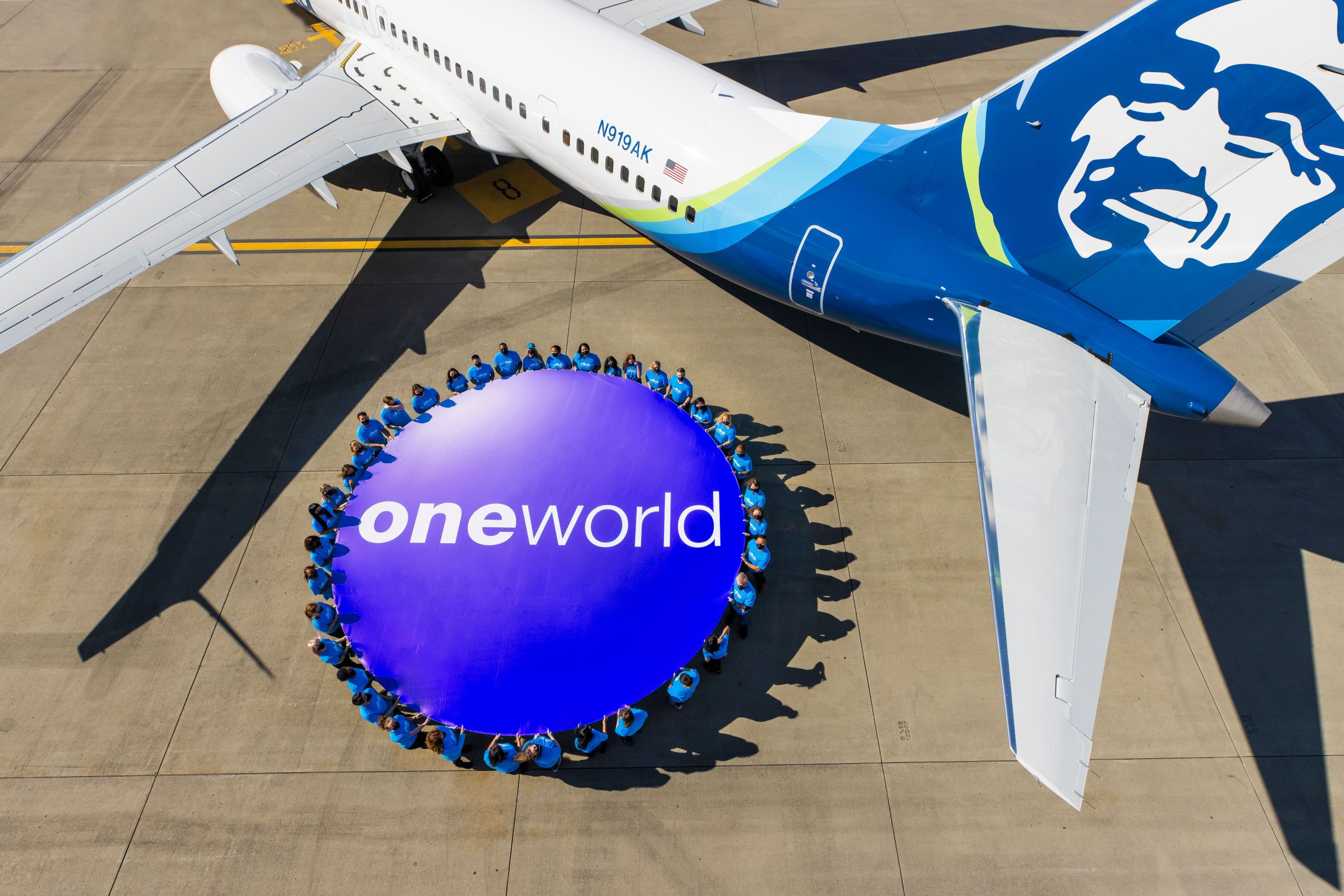 An Alaska Airlines aircraft next to a oneworld banner.