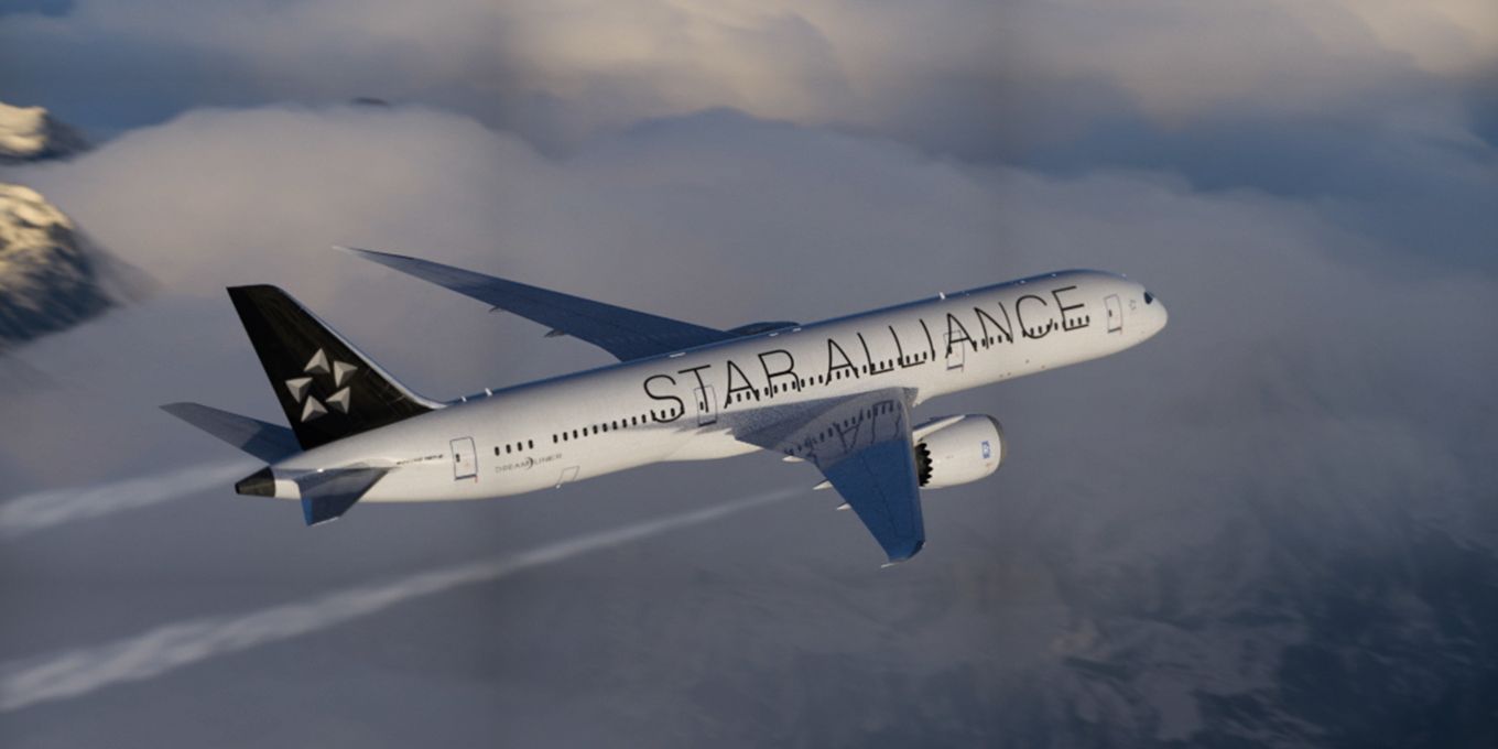 A Star Alliance liveried Boeing 787 Dreamliner flying above the clouds.