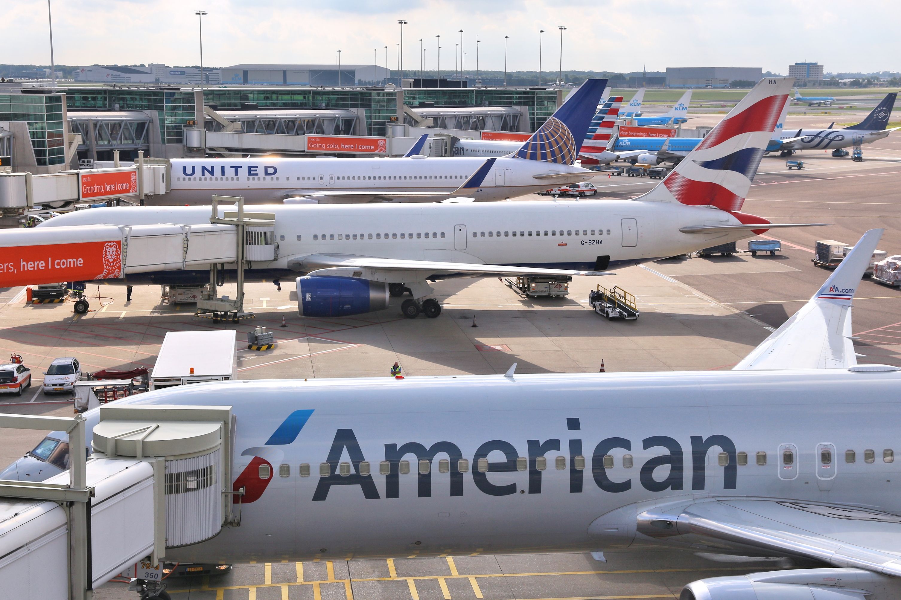 British Airways, American Airlines, And United Airlines Aircraft parked at the gate.