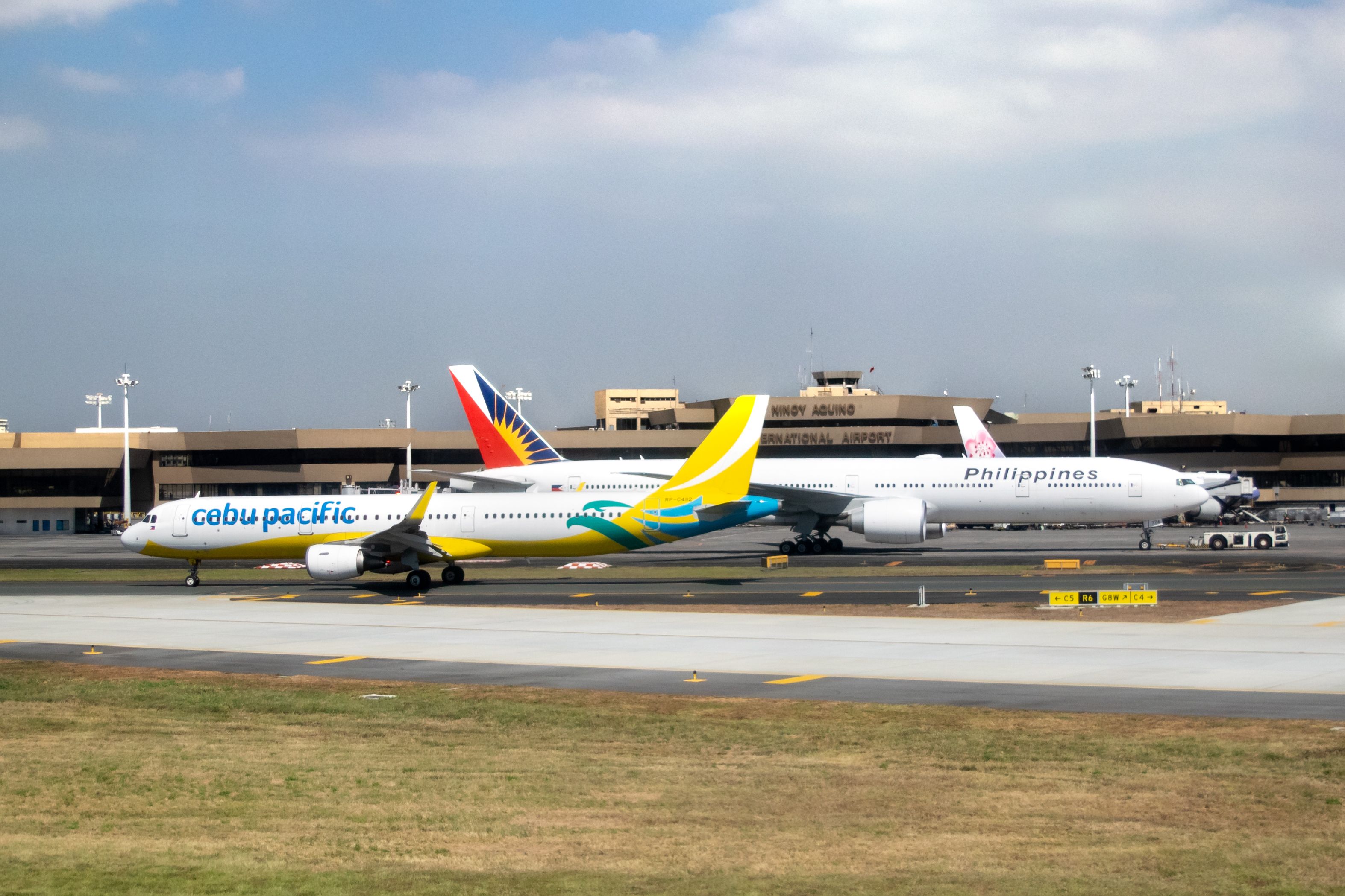 A Cebu Pacific Airbus A321 taxis in front of a Philippine Airlines Boeing 777 at Manila's Ninoy Aquino International Airport