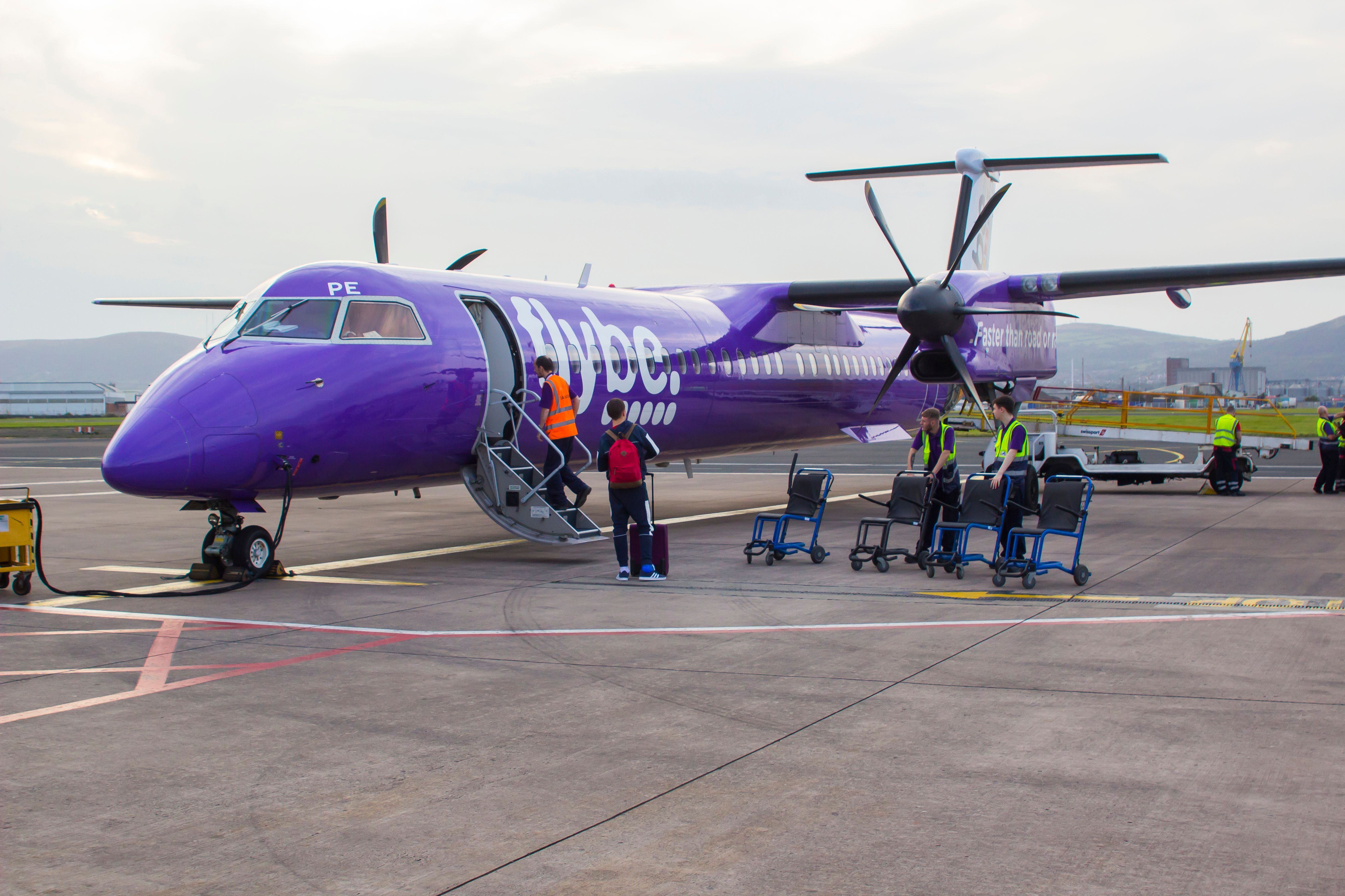 21 September 2019 A FlyBe Dash 8 Commercial Airliner with luggage and passenger handlers on the apron at George Best City Airport in Belfast Northern Ireland