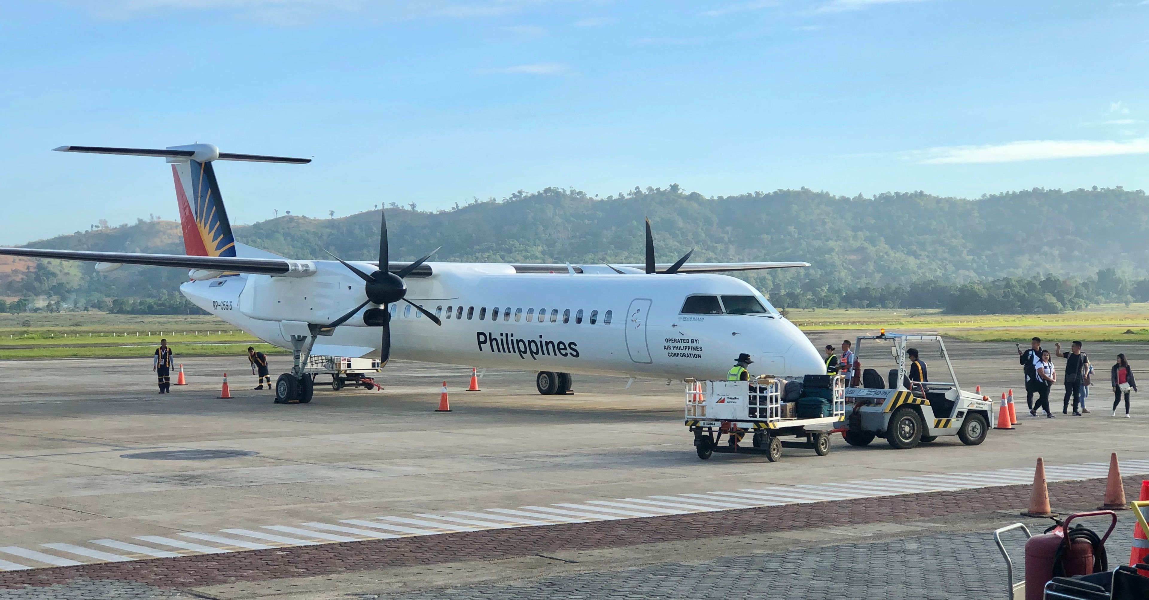 A Philippine Airlines DeHavilland Dash 8 turbo prop Aircraft parked at the airport.