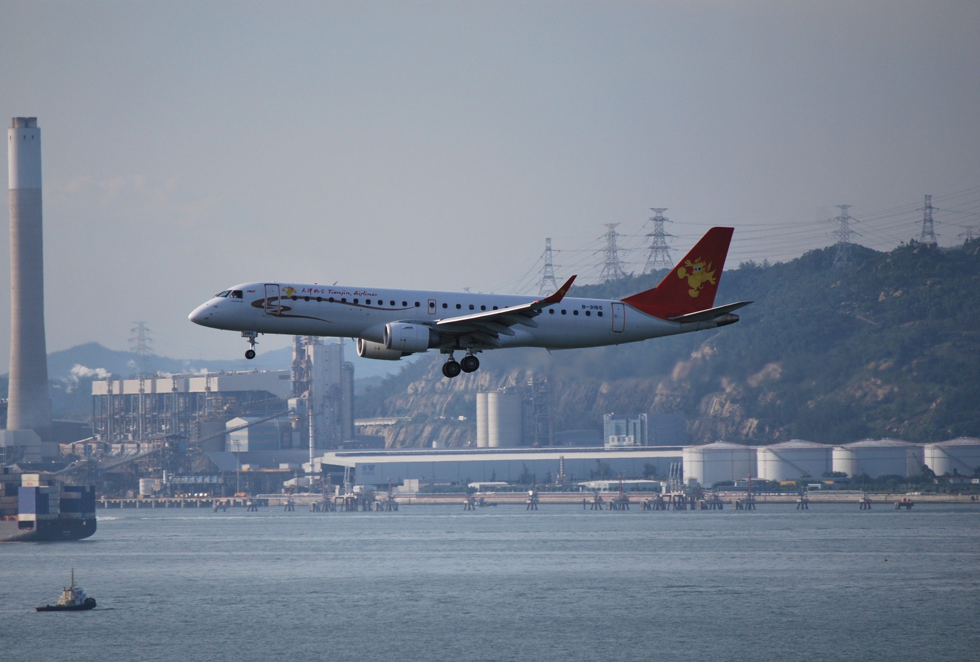 A Tianjin Airlines Embraer aircraft flying over water.