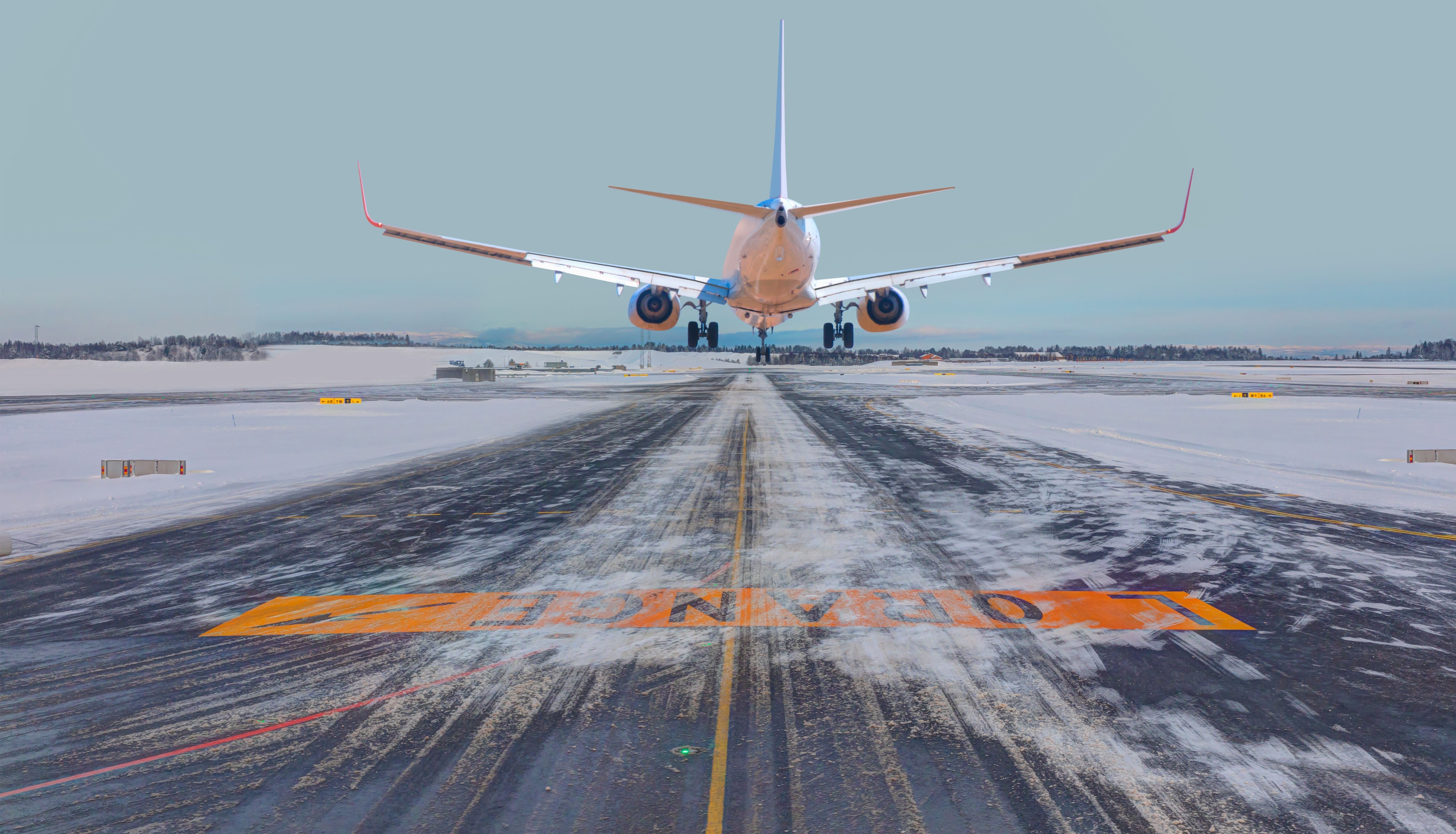 An aircraft landing on a snow-cleared runway.