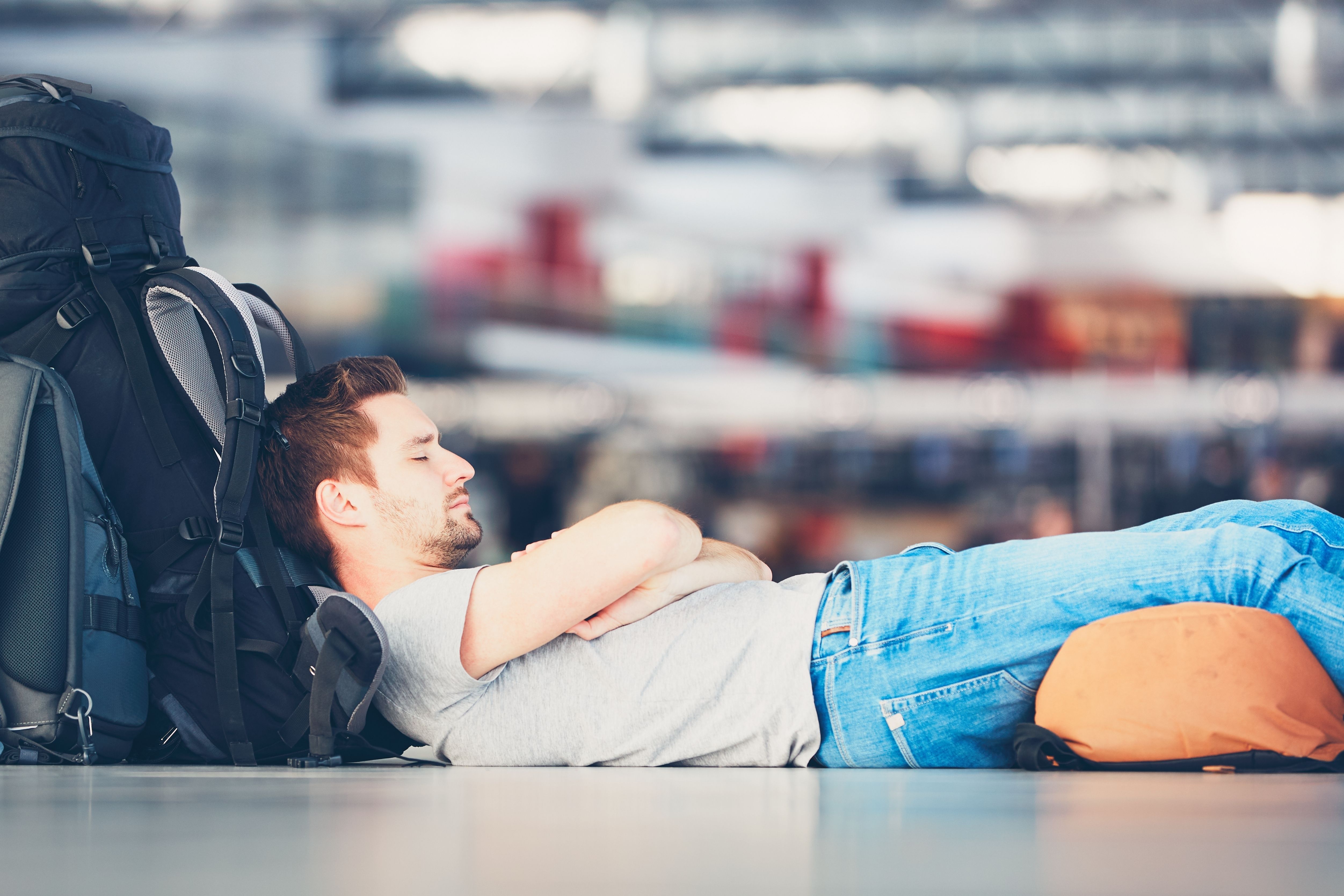 A man sleeping with his luggage in an airport terminal. 