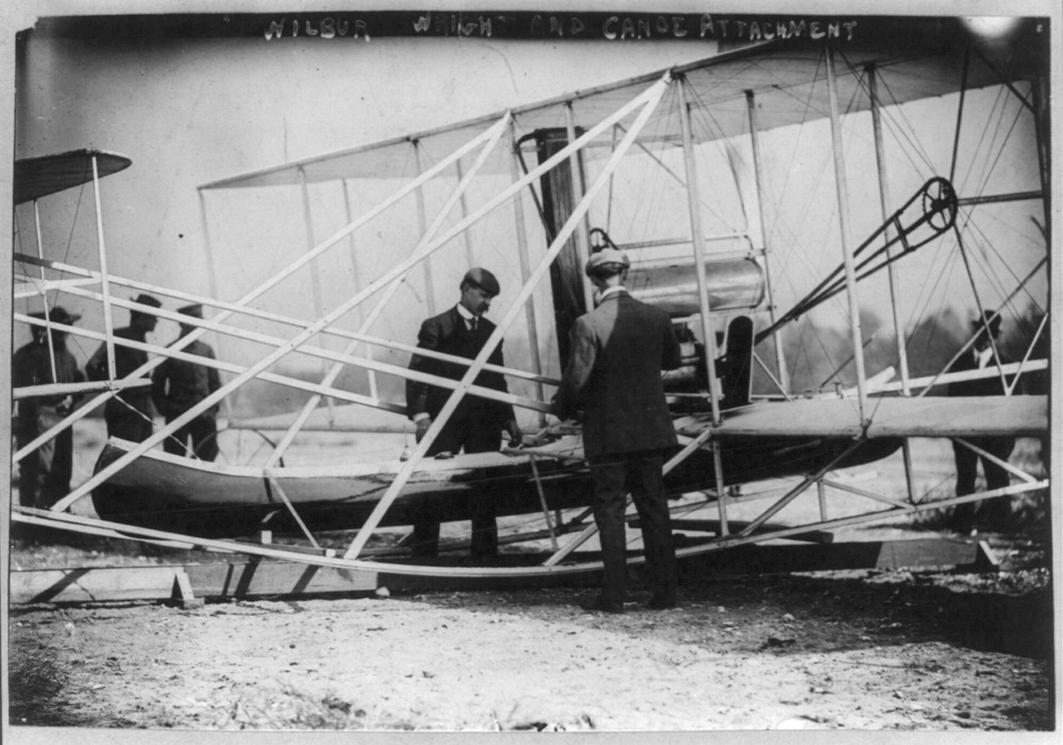 Wilbur Wright and Charles Taylor examining a canoe attachment to an aircraft.