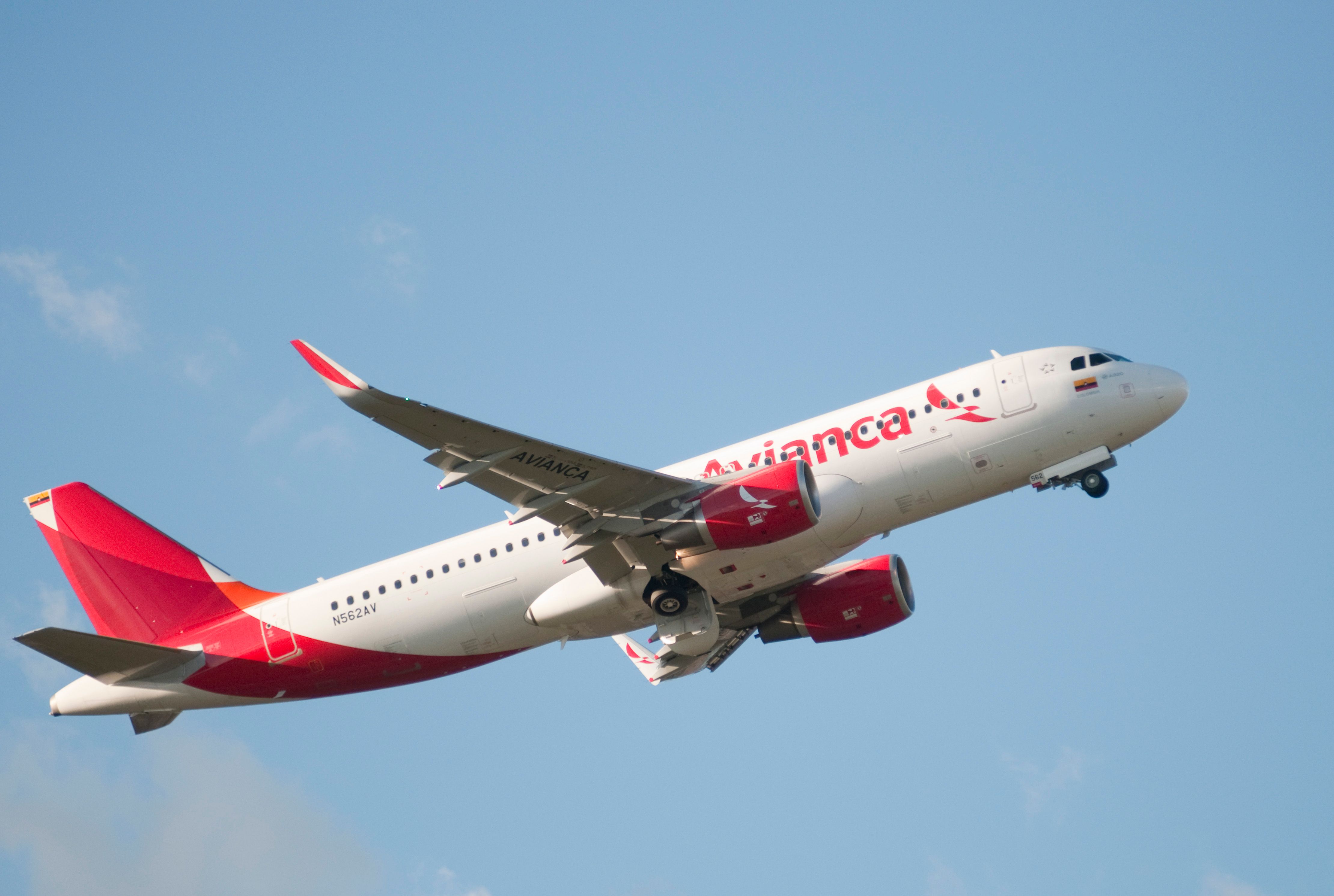 An Avianca Airbus A320 flying with a blue sky in the back