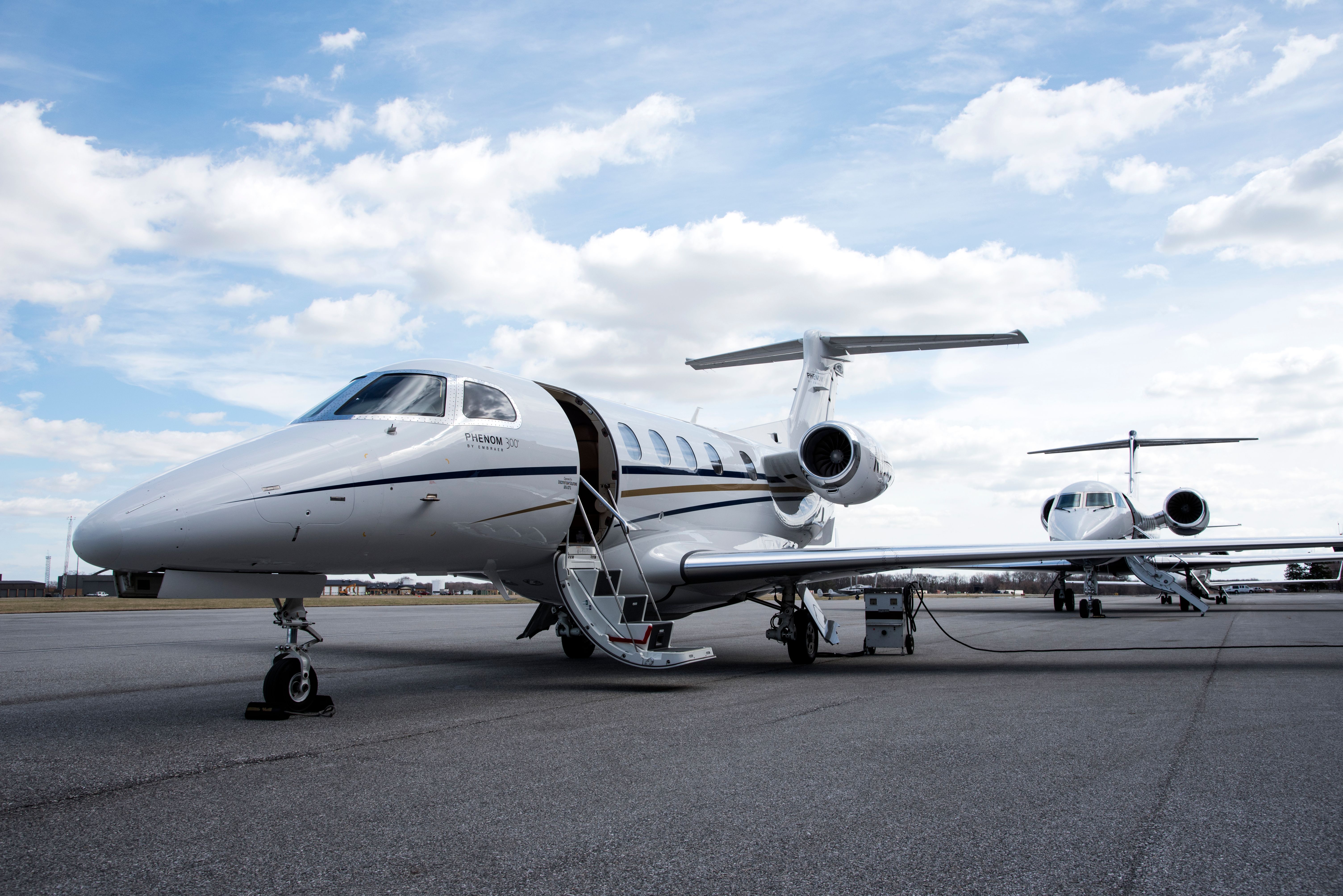 Two Embraer Phenom 300s parked at an airport.