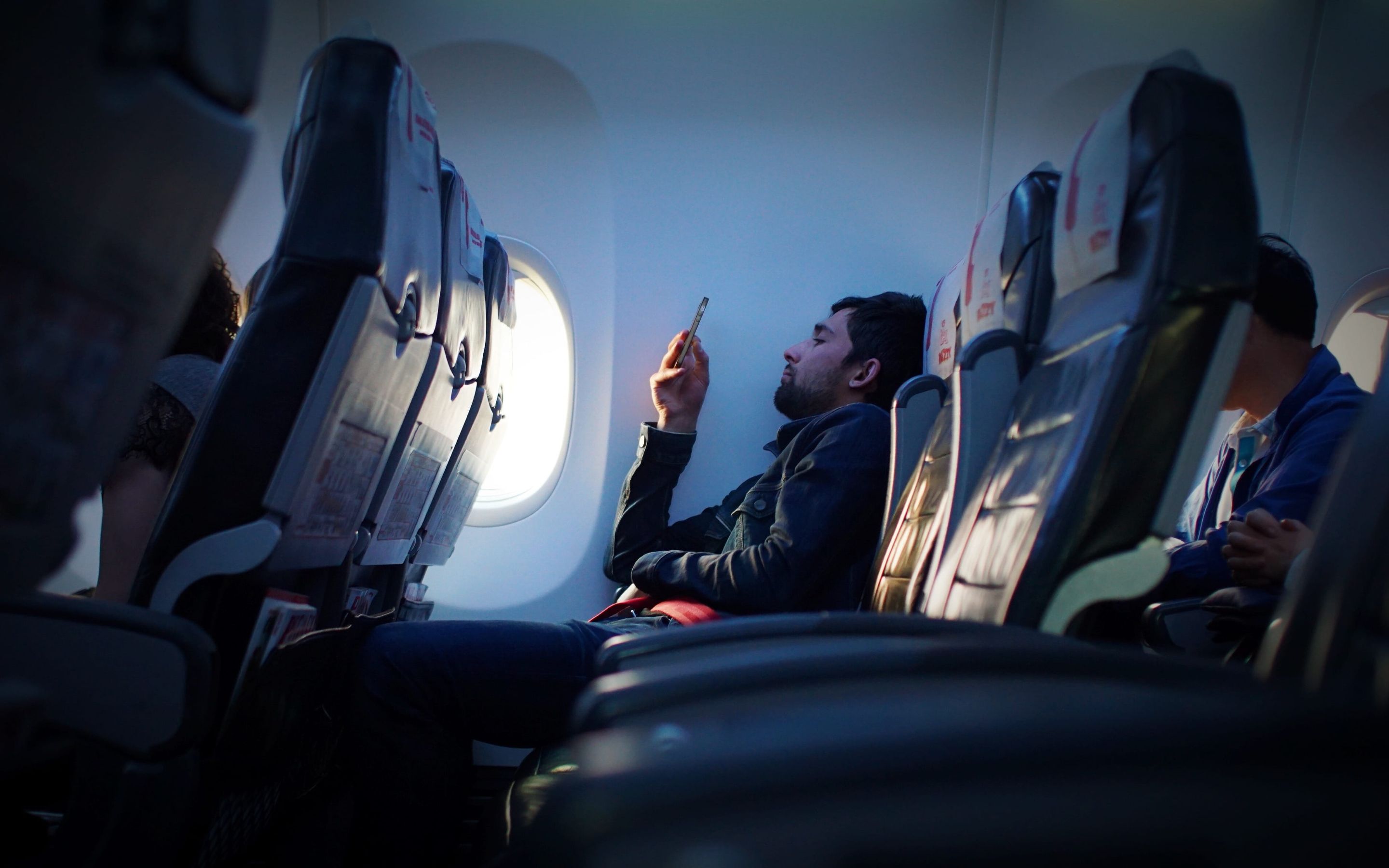 A Man using phone on plane.