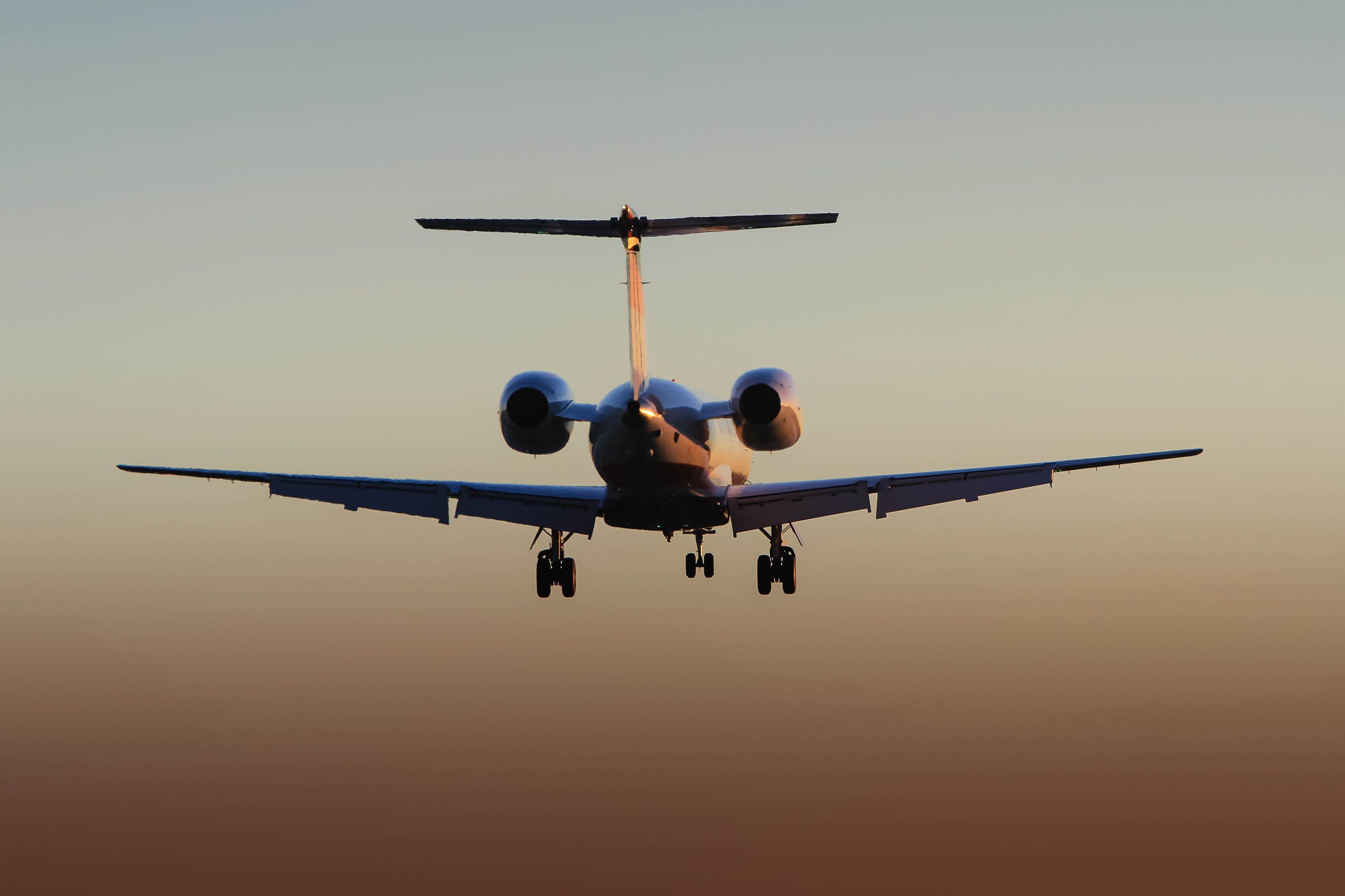 Rear view silhouette of private corporate jet in flight at sunset