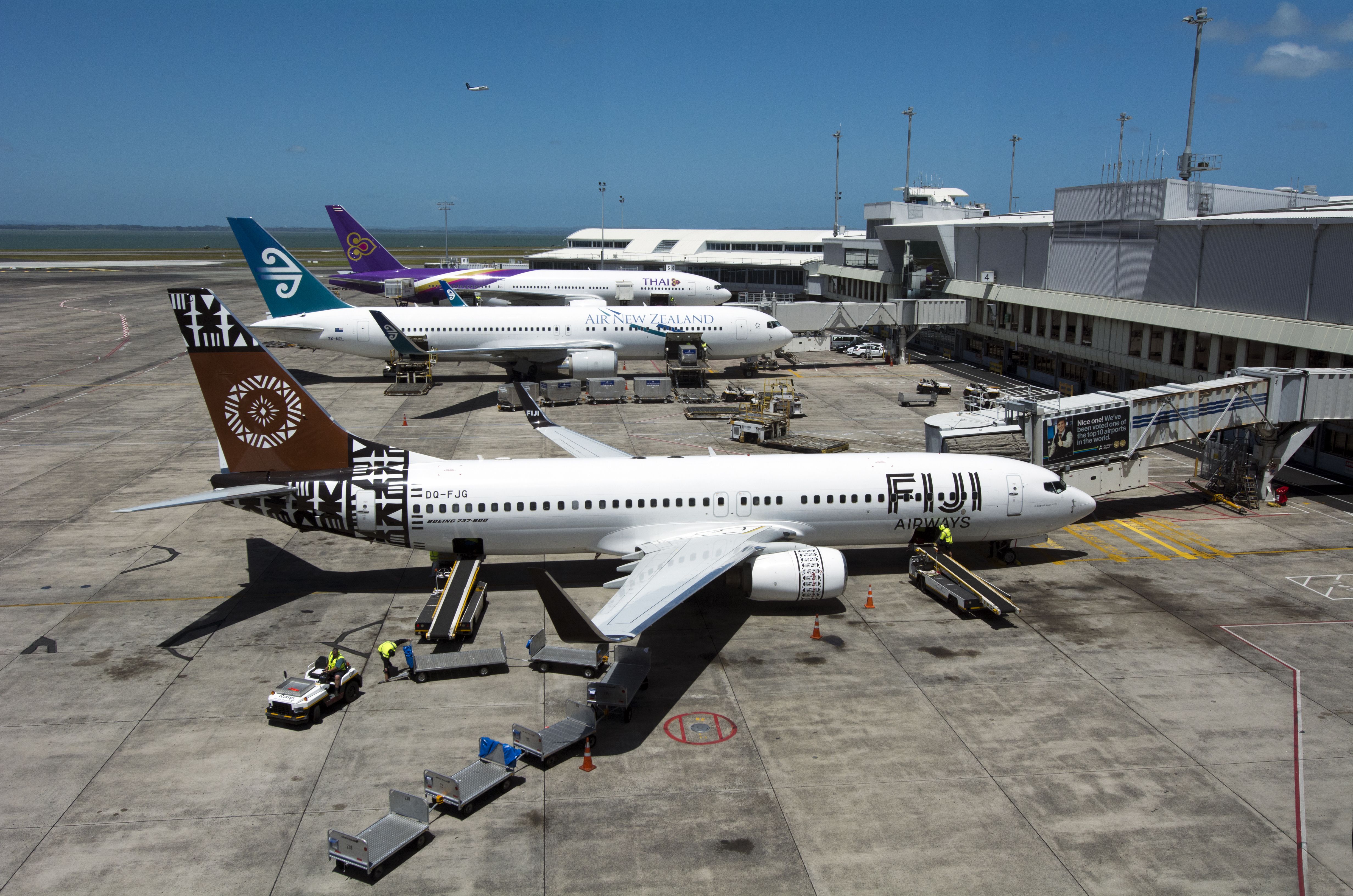 Fiji Airways, Air New Zealand, and Thai Airways Aircraft parked at Auckland Airport gates.