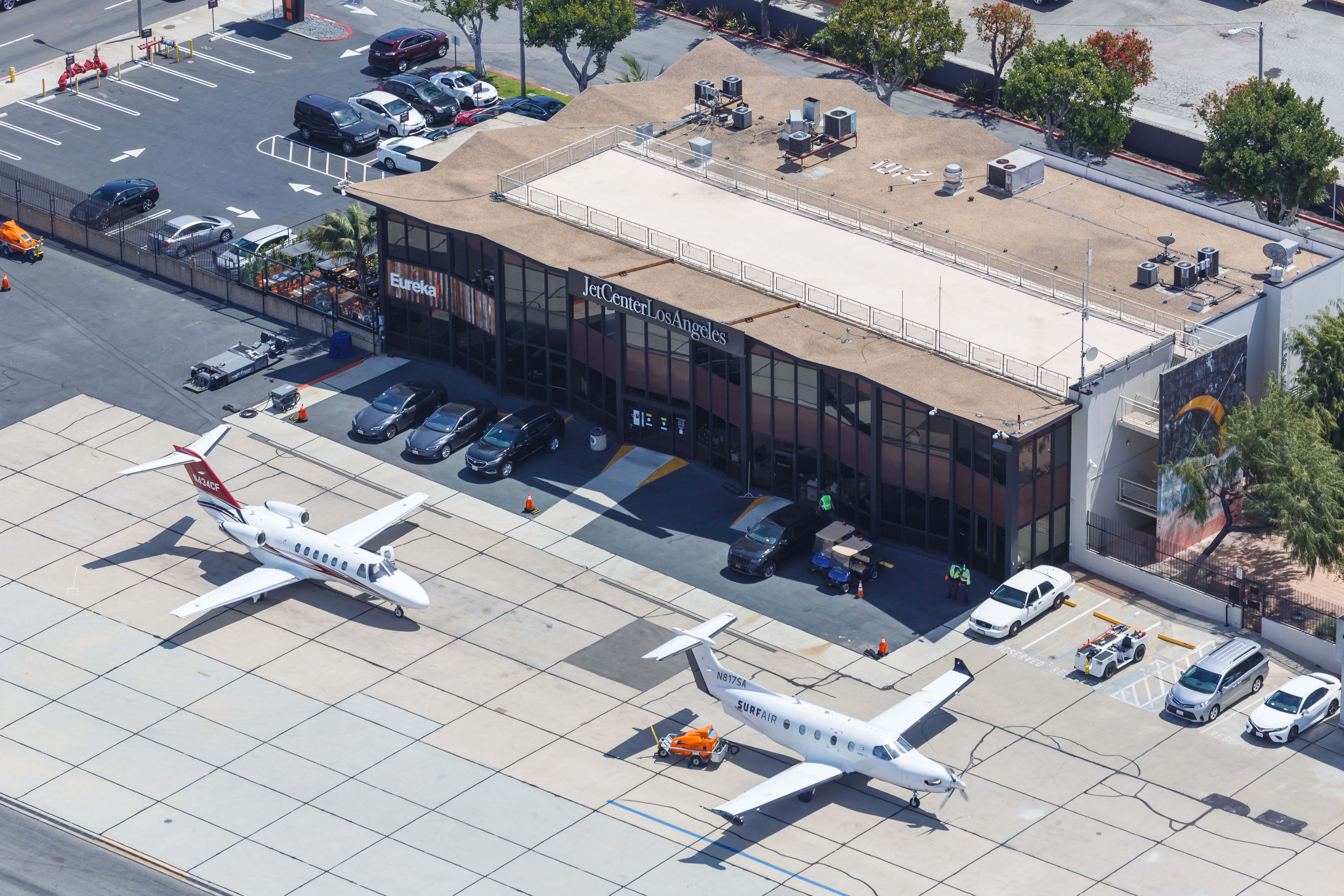 Two small aircraft, including one Surf Air Pilatus PC-12, parked at a private terminal in Los Angeles.