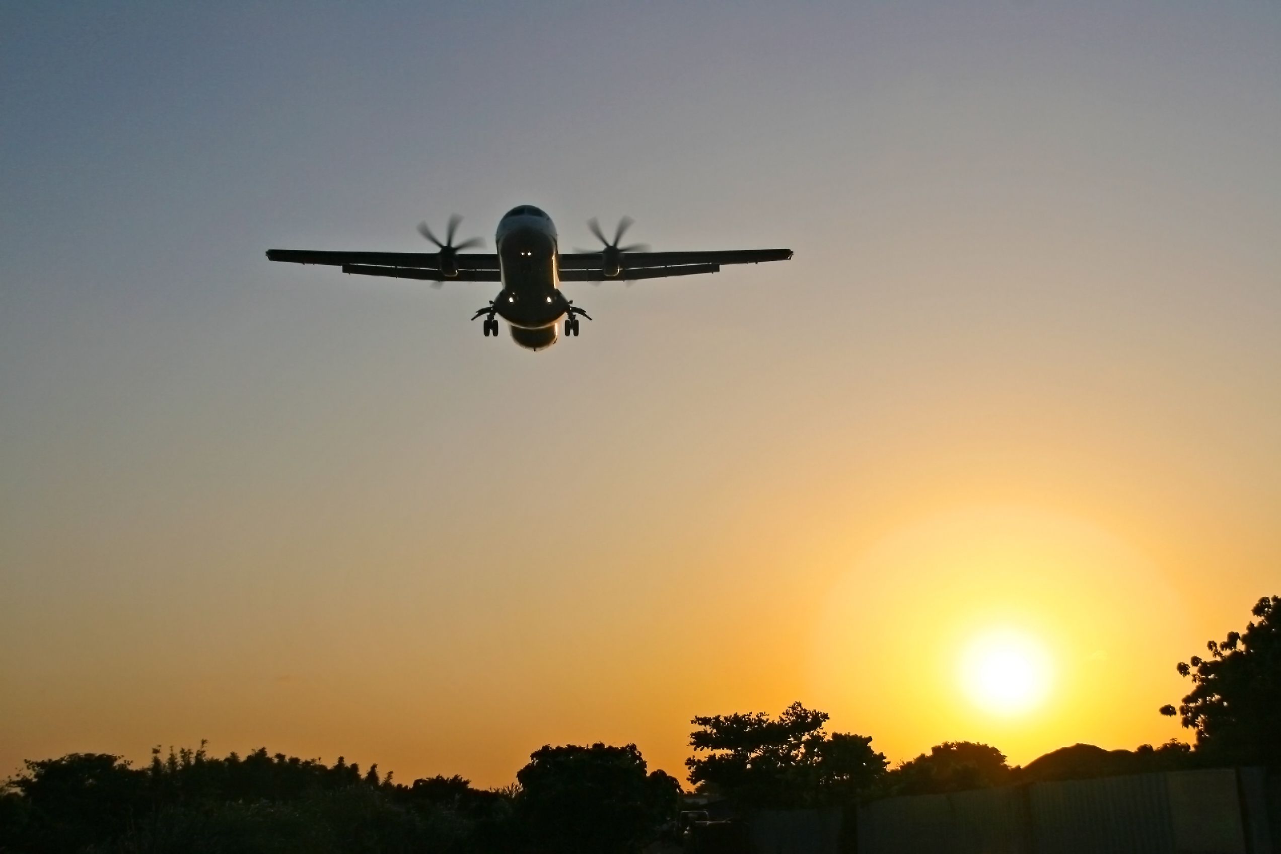An ATR aircraft flies at low attitude and beautiful sunset behind