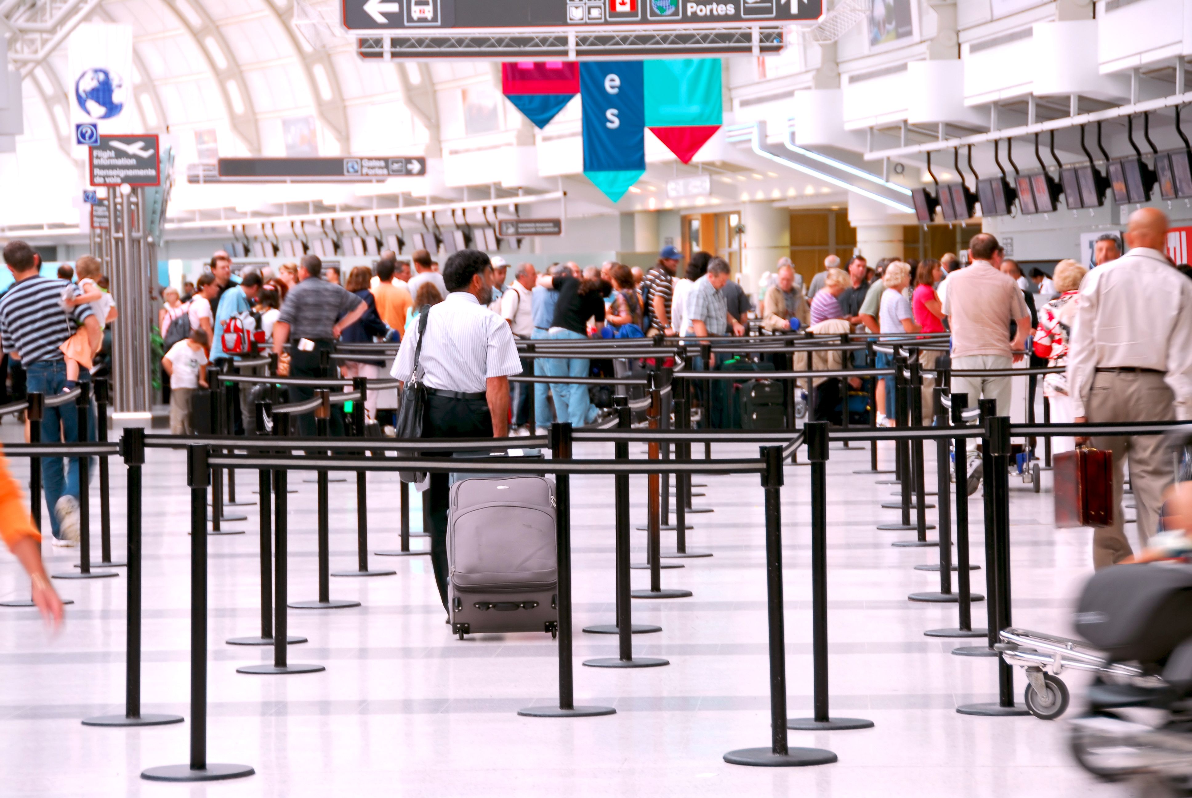 Passengers waiting in check-in queues at an airport.