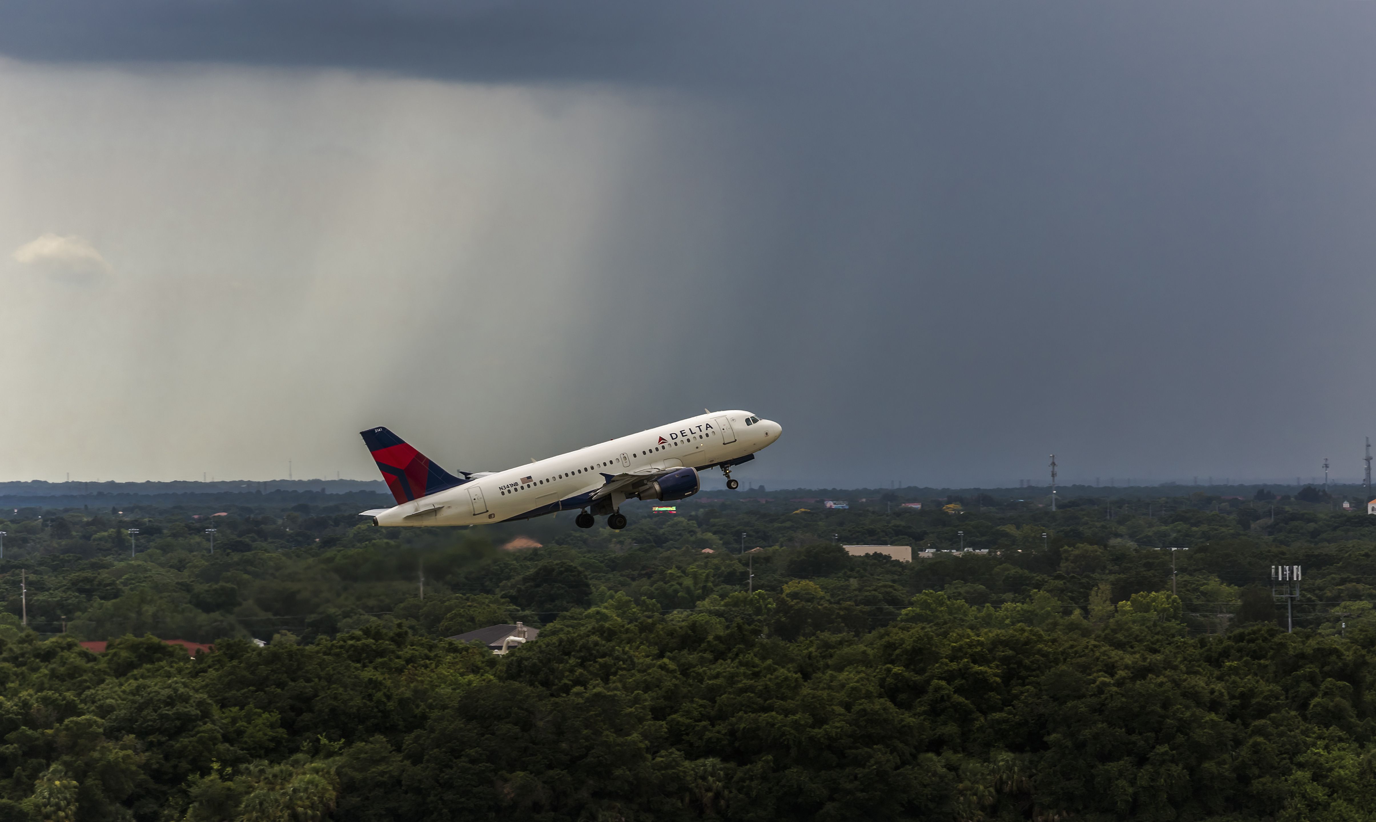Delta Air Lines Airbus A319 departing from Tampa International Airport with storm in the background.