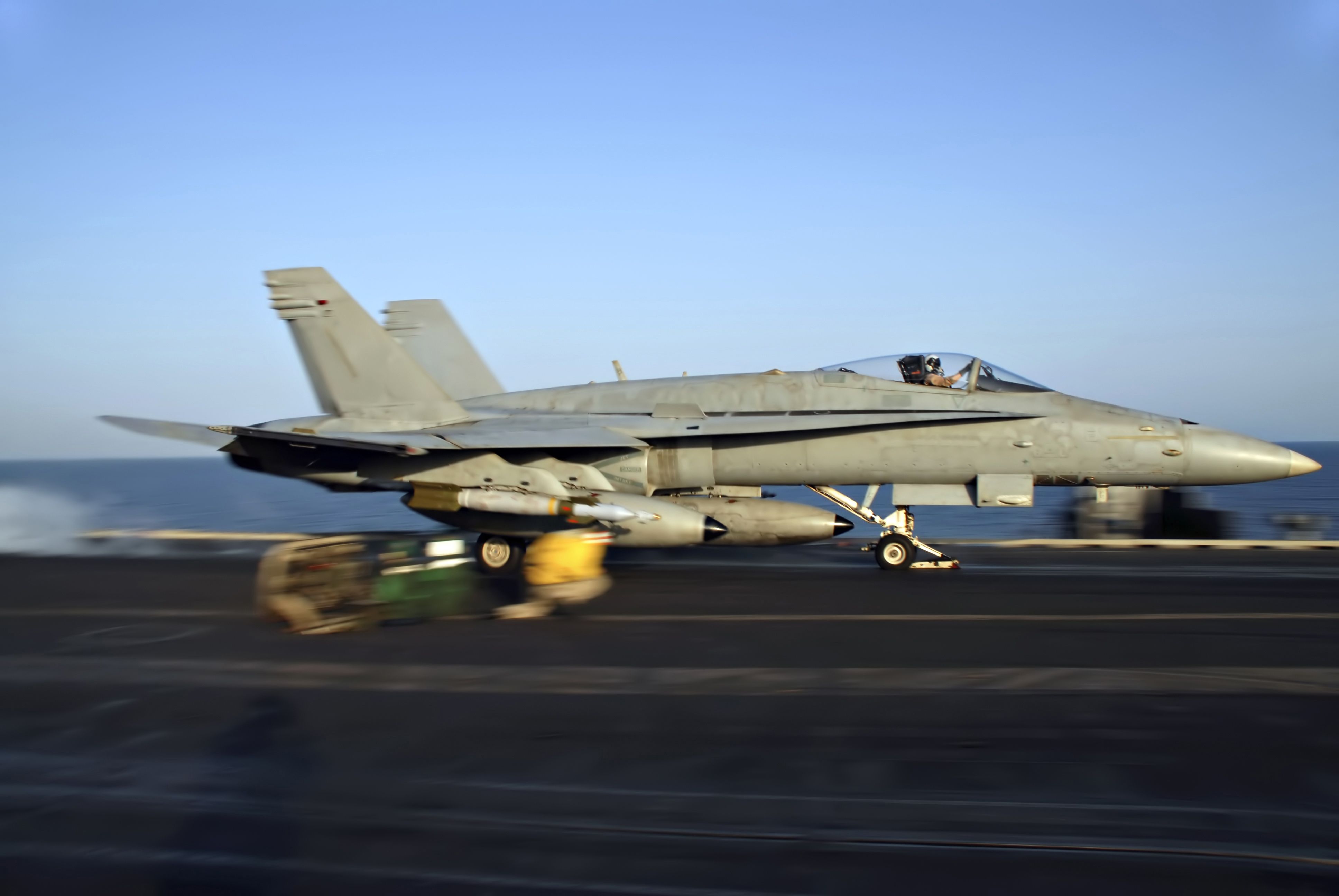 An F-18 Hornet rockets down the deck of an aircraft carrier.
