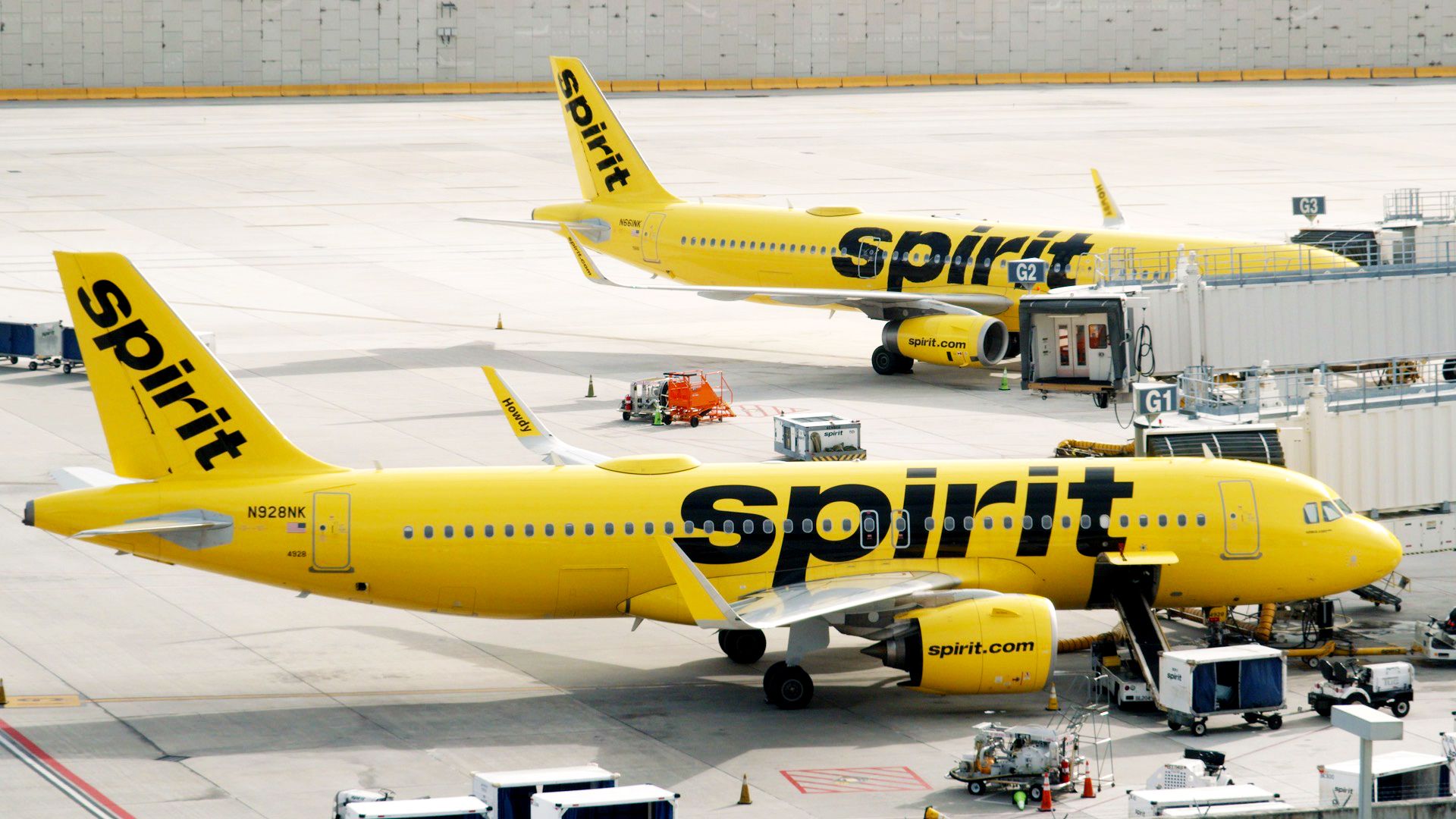 Two Spirit Airlines Aribus A320s parked at an airport.