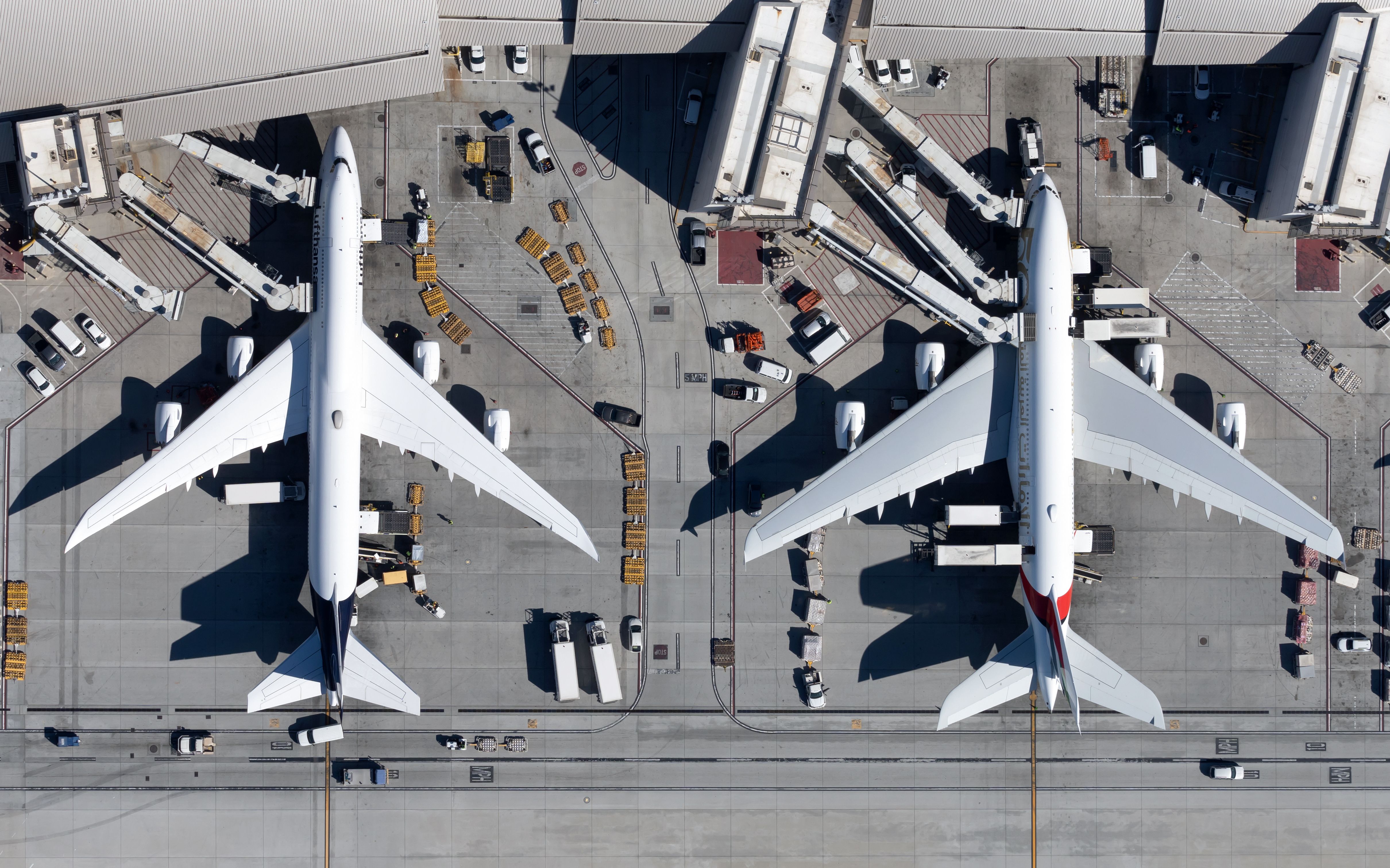 An overhead view of multiple widebody aircraft at gates at LAX airport.