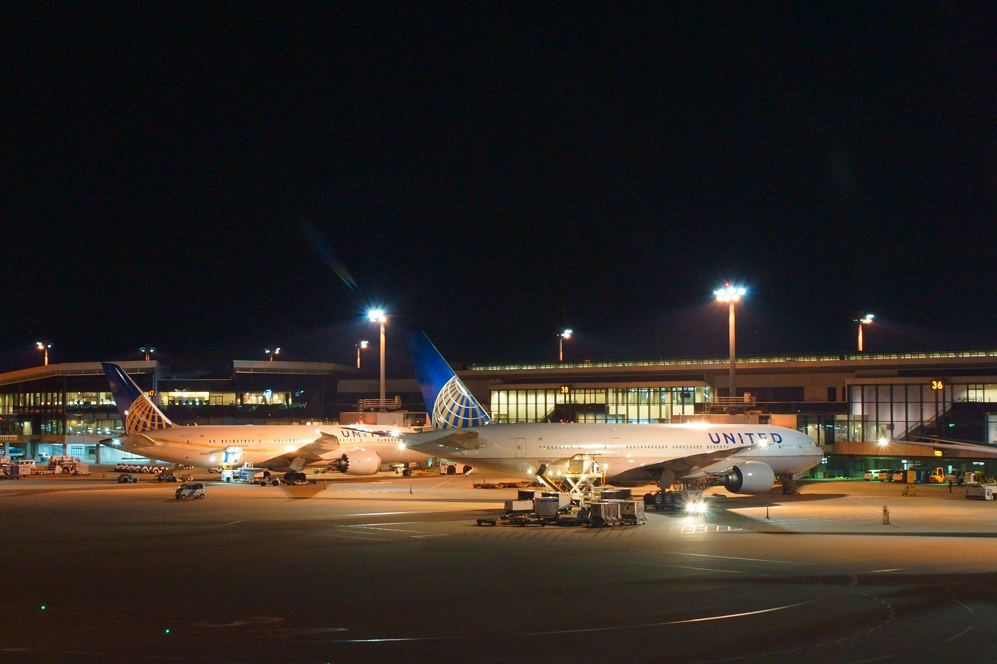 Two United Airlines aircraft parked at Tokyo Narita Airport at night.