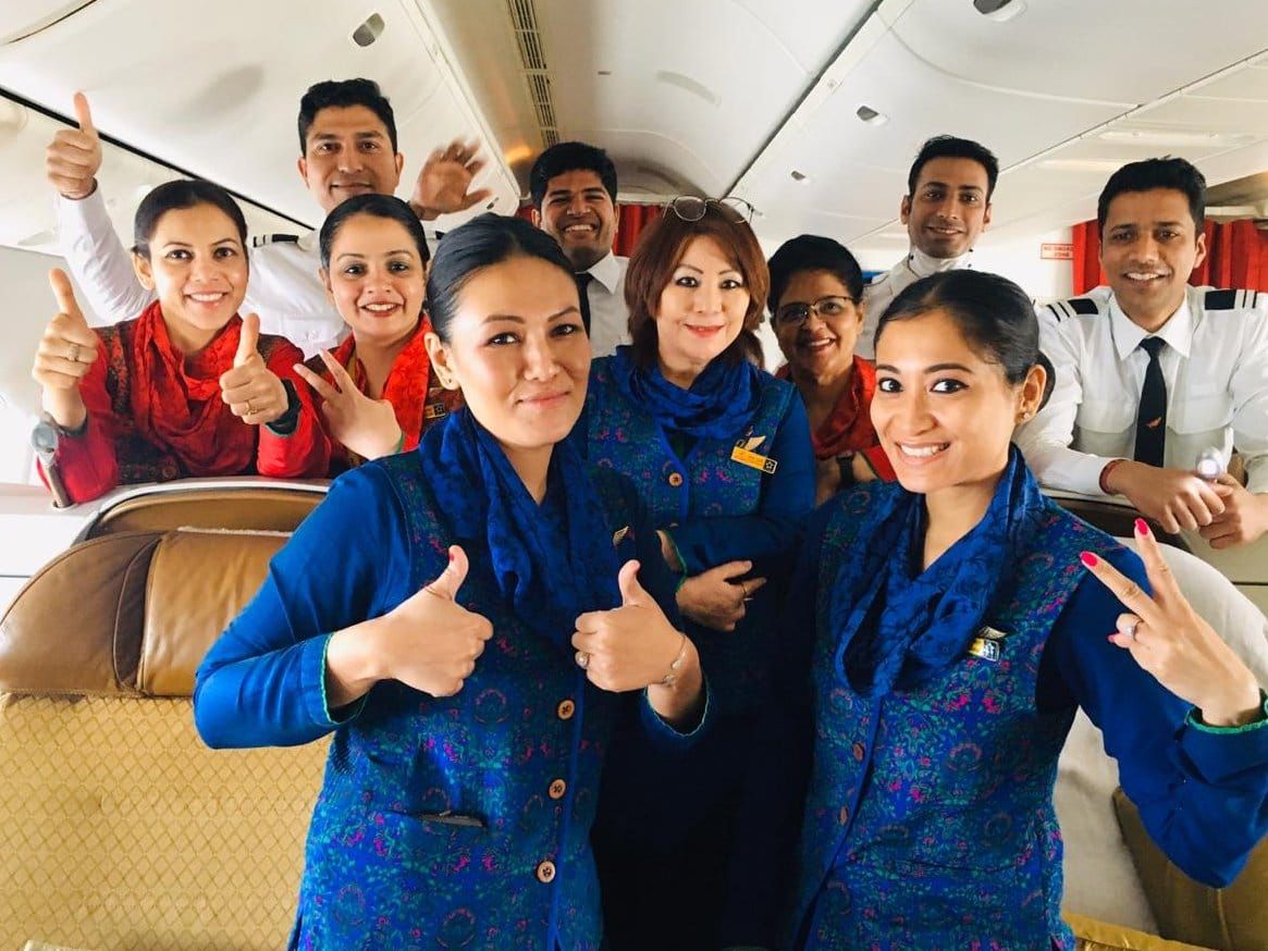 Air India flight and cabin crew members taking a photo together in a business class cabin.